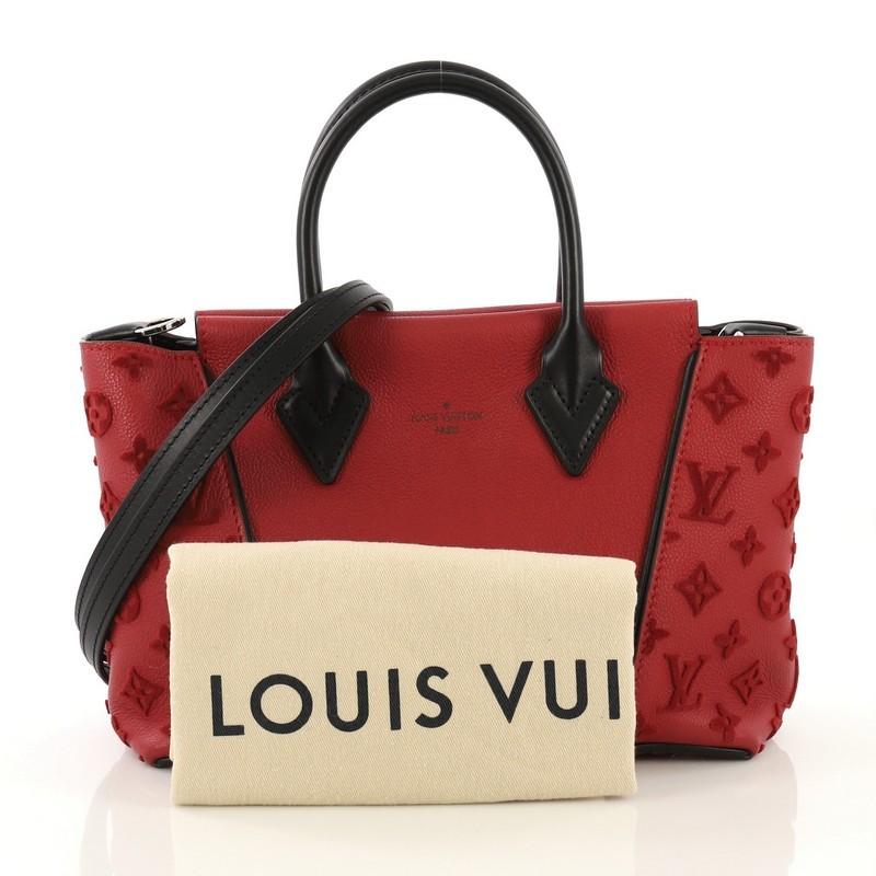 This Louis Vuitton W Tote Veau Cachemire Calfskin BB, crafted from red veau cachemire calfskin leather, features dual rolled handles, expansive sides with tufted monogram embossed patterns, and silver-tone hardware. Its magnetic snap closure opens
