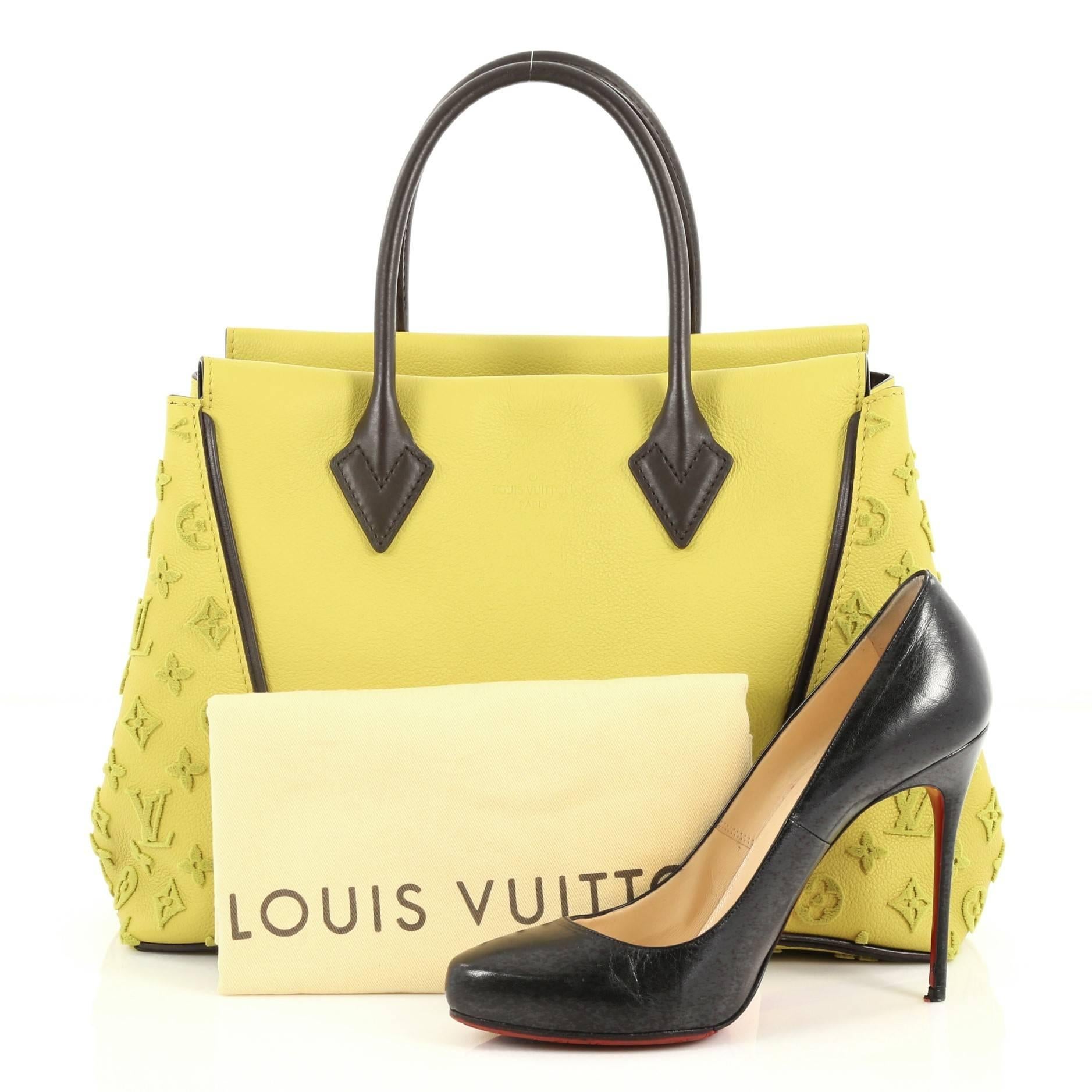 This authentic Louis Vuitton W Tote Veau Cachemire Calfskin PM is a collector's dream with an edgy and youthful design made for the modern woman. Crafted yellow veau cachemire leather, this luxurious and elegant tote features dual-rolled handles,