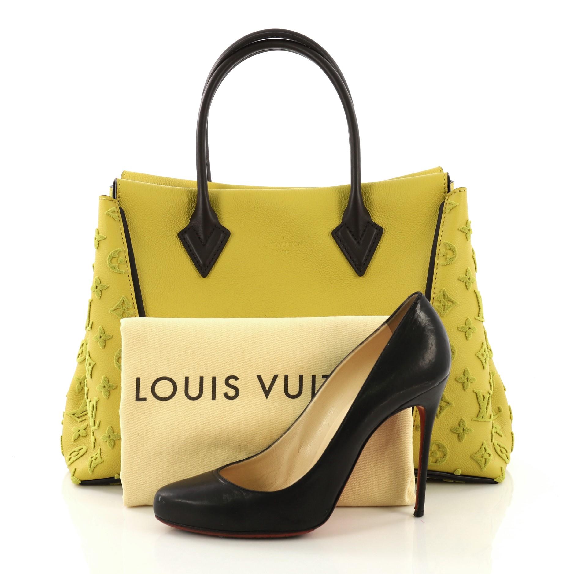 This Louis Vuitton W Tote Veau Cachemire Calfskin PM, crafted from yellow veau cachemire calfskin, features dual rolled handles, expansive sides with tufted monogram embossed patterns and silver-tone hardware. Its magnetic top closure opens to a