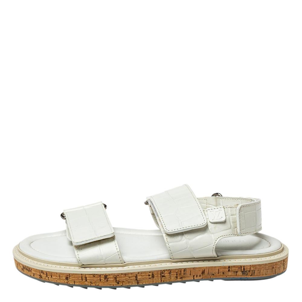 Ideal for a trendy appeal, these stylish sandals by Louis Vuitton are crafted using croc-embossed leather. They come with a white hue and velcro straps. An open-toe design elevates the overall look. They make excellent picks for a sleek look, that