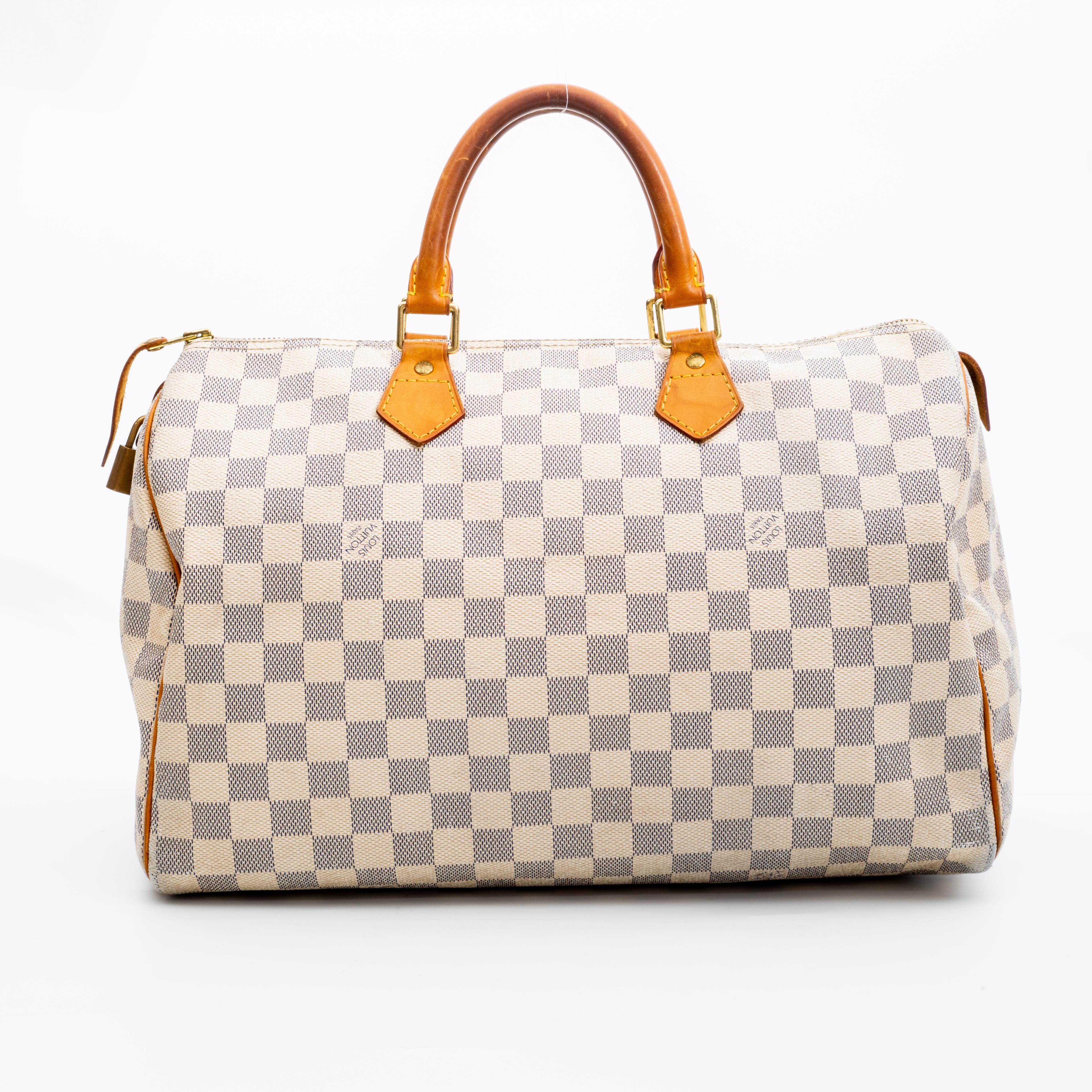 The Speedy bags was made popular by Audrey Hepburn and this model measures 35 cm long. 
The bag is made out of Damier Azur coated canvas with tanned natural cowhide leather finishes. This bag features rolled leather handles, brass hardware, top zip