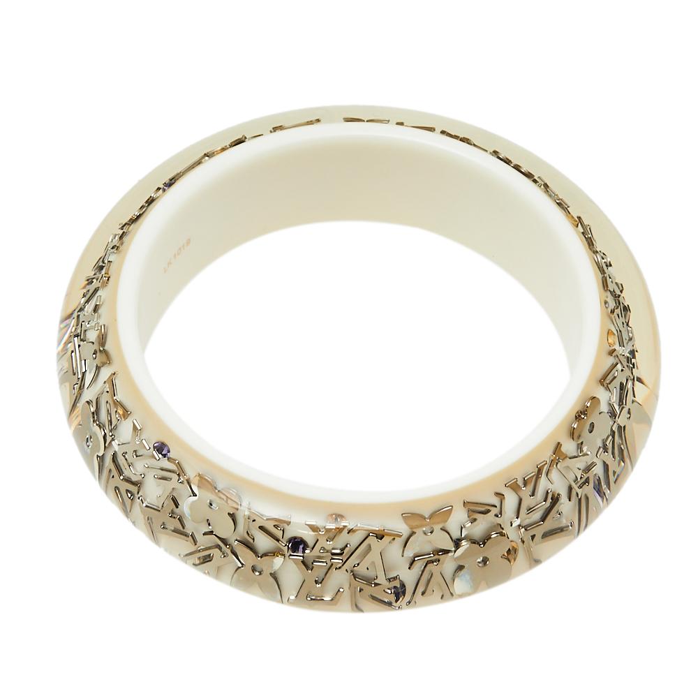 Louis Vuitton, one of the most recognizable fashion brands, brings this chic and elegant bangle. The base of the bangle is white and is studded with the iconic Louis Vuitton monograms in silver. The motifs are sealed in with clear resin, giving the