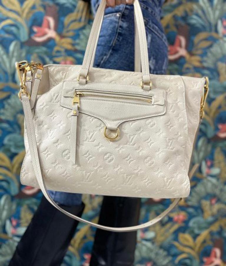 Louis Vuitton bag Ombre Lumineuse model Empreinte line made of white monogram leather with golden hardware. It has a zip closure, very large inside and equipped with pockets. The bag has a double handle and a removable shoulder strap. It is in