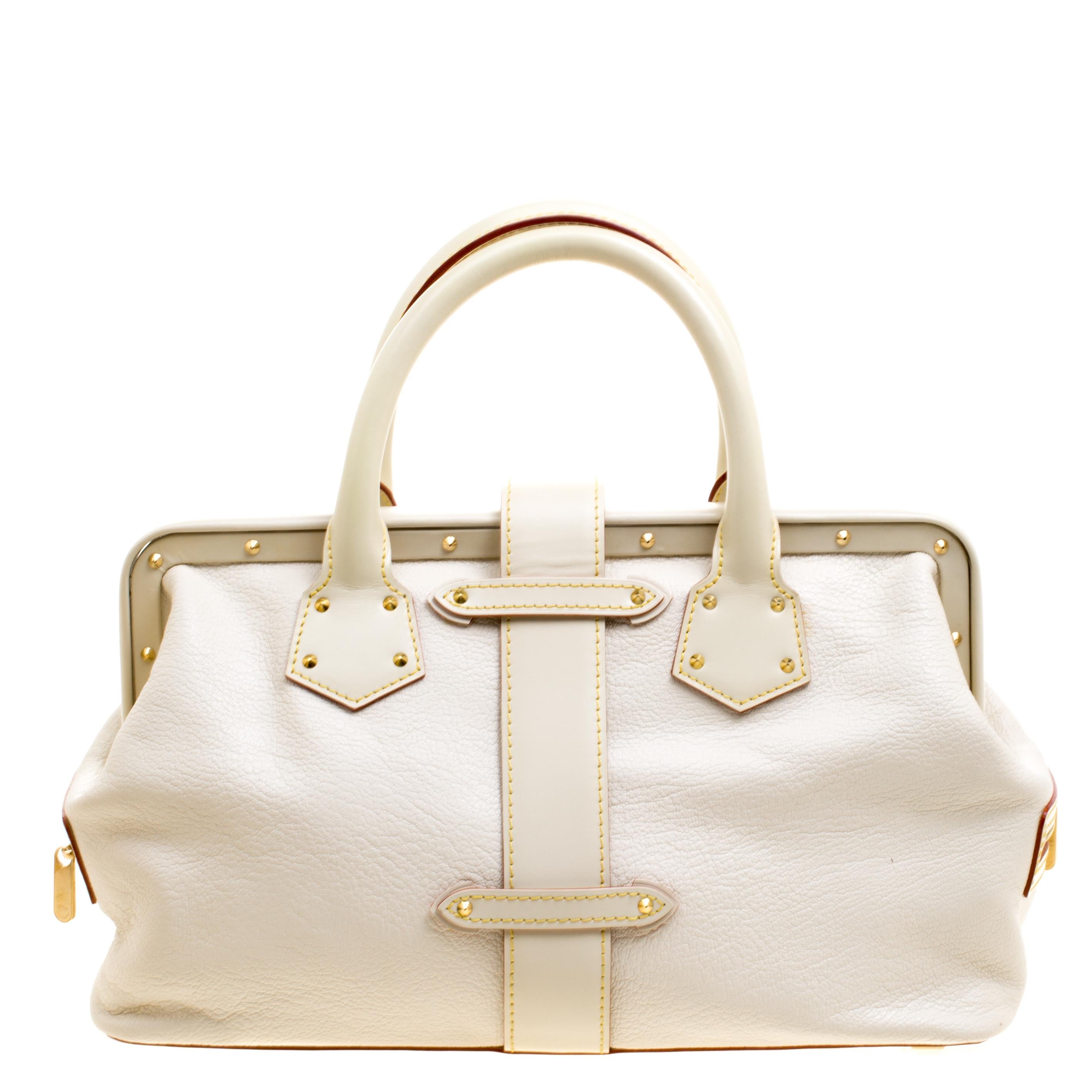 This posh L'Ingenieux PM Bag from Louis Vuitton is shaped in a stunning white Suhali leather and detailed with gorgeous gold-tone accents that lend it an elegant look. It features two rolled top handles, a sturdy top and protective base studs that