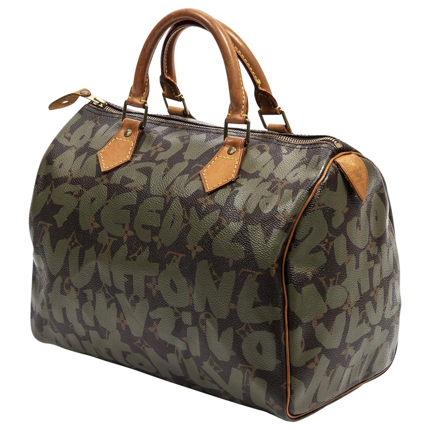 An iconic collab between the legendary Stephen Sprouse and Louis Vuitton. This 2001 beauty is detailed in brown coated canvas with green monogram graffiti, golden brass hardware, dual leather rolled top handles and leather trim. The zipped closure