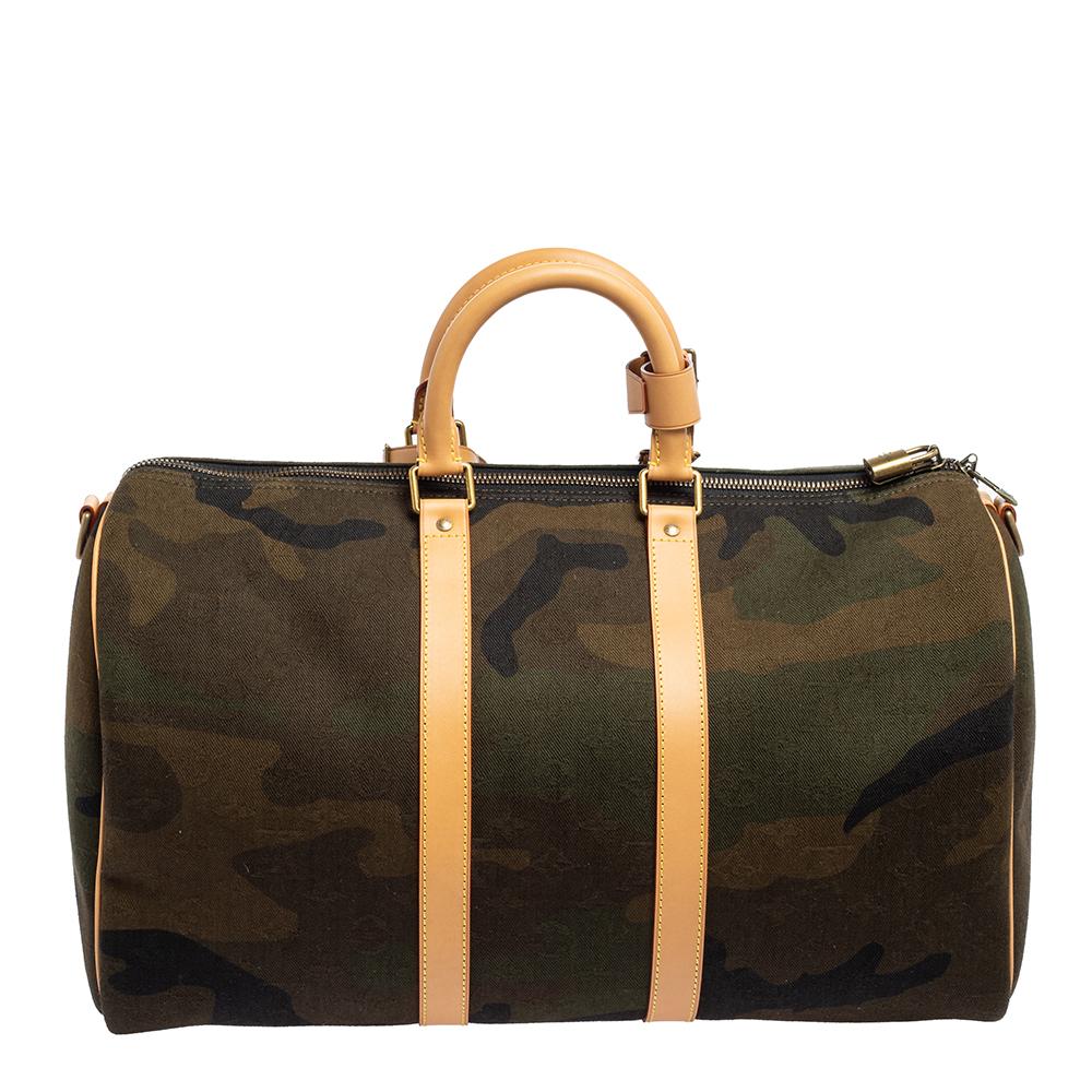 This Keepall Bandouliere 45 bag from the House of Louis Vuitton will be your favorite travel accessory in no time. It is made from Monogram Camouflage canvas and leather, along with gold-toned hardware. A capacious interior space, dual handles, and