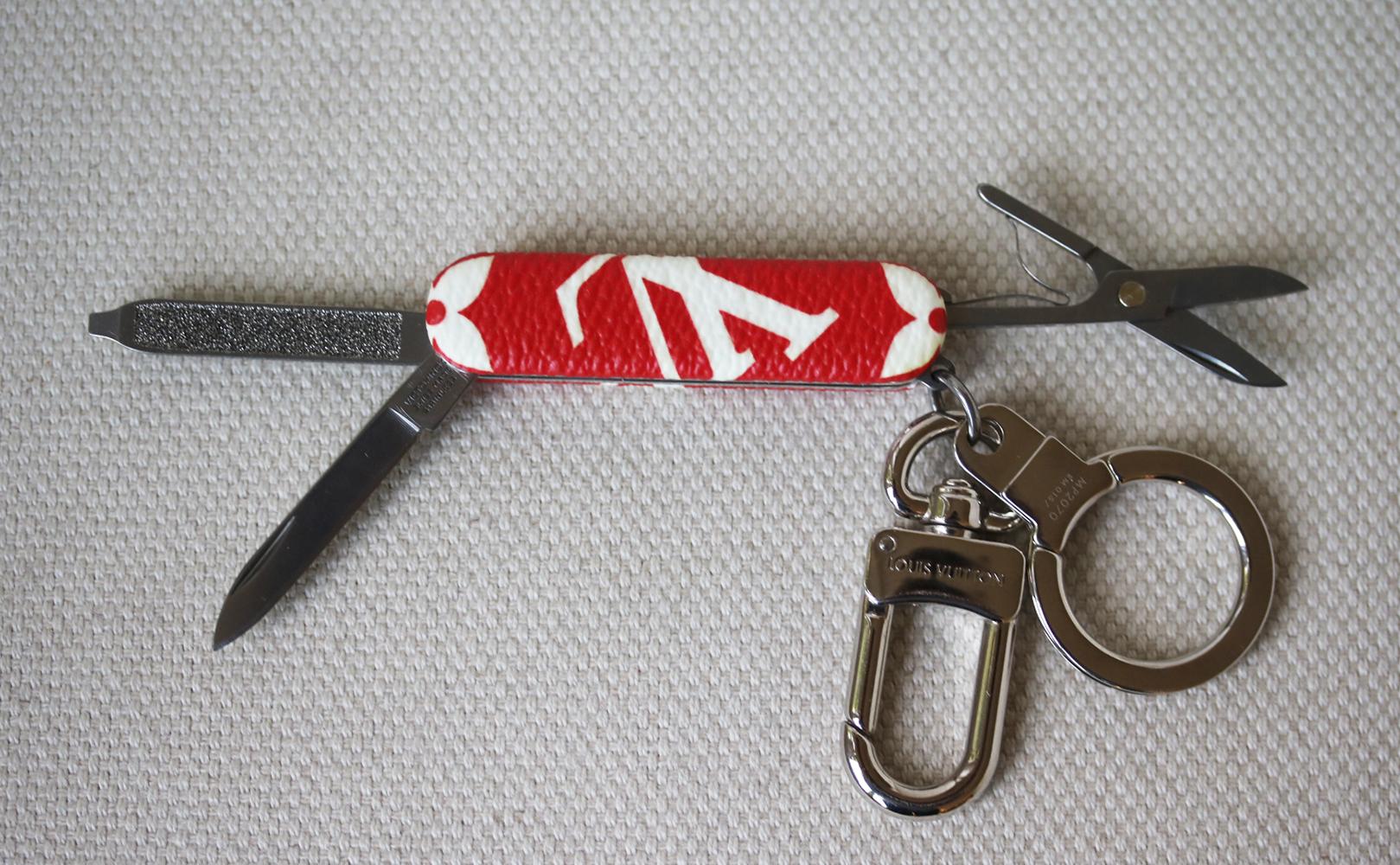 This key ring from Louis Vuitton can also be used as a pocket knife. Lined in Louis Vuitton’s iconic red monogram coated canvas and features a silver-tone ring and snap hook along with concealed knives and a pair of scissors. Silver-tone hardware.
