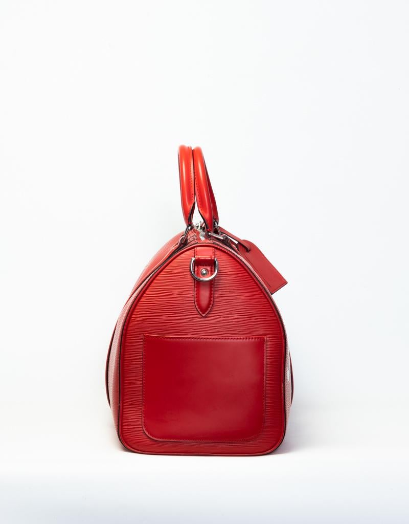 This iconic Keepall bag by Louis Vuitton and Supreme is made of red epi leather and features white Supreme logo, a detachable red leather shoulder strap, silver tone hardware, a two-way zipper closure, an exterior slip pocket & an interior zipper
