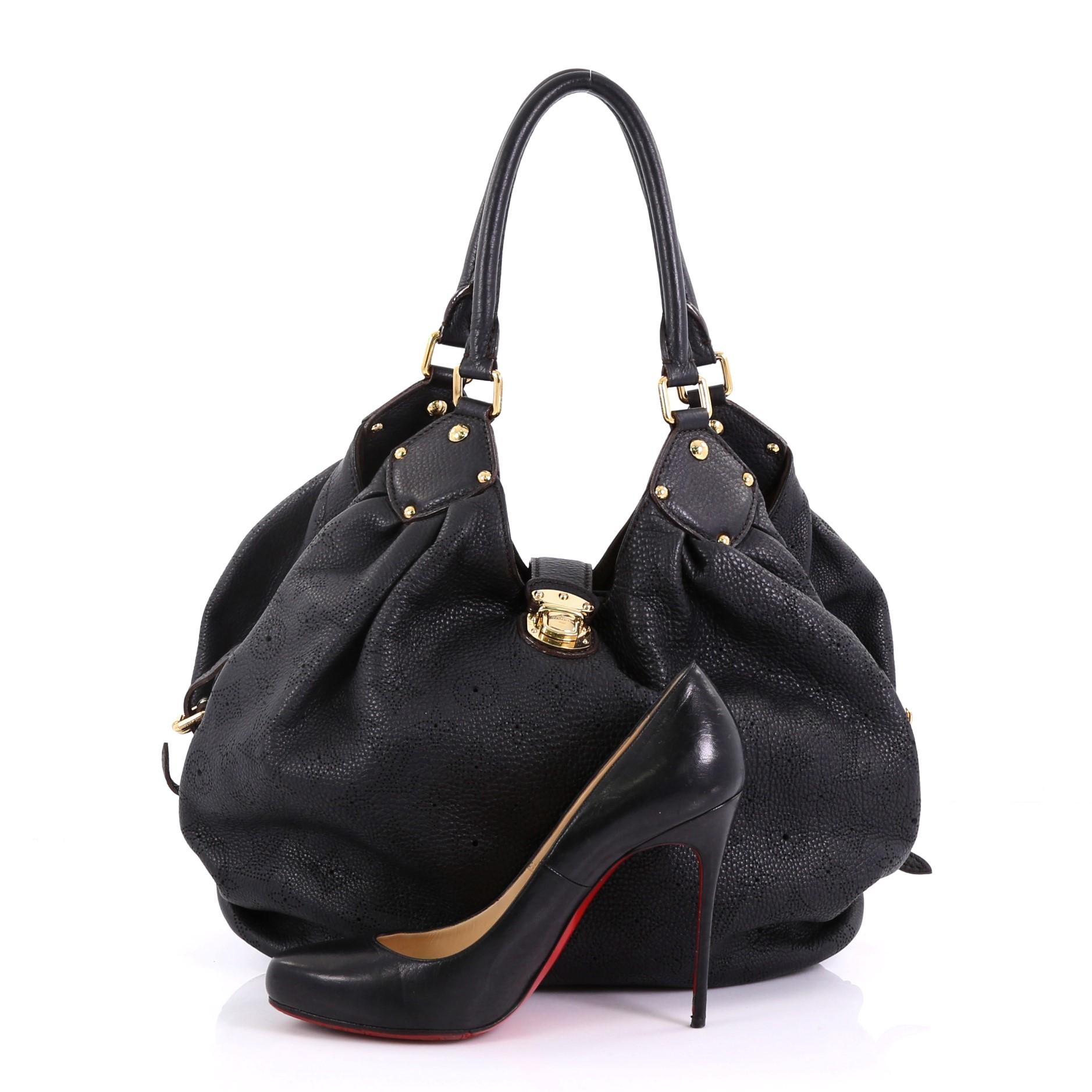 This Louis Vuitton XL Hobo Mahina Leather, crafted from black monogram mahina leather, features dual rolled handles, buckle and stud details, and gold-tone hardware. Its engraved top flap push-lock closure opens to a brown microfiber interior with