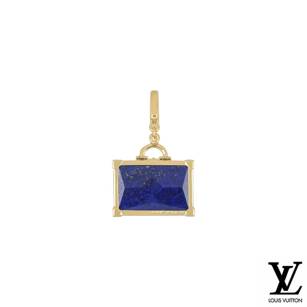 An 18k yellow gold suitcase charm by Louis Vuitton. The charm is in the design of a suitcase set with a lapis lazuli centre with yellow gold borders. The charm features a push clasp and measures 1.50cm in width and 2.20cm in length and has a gross