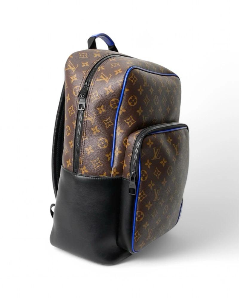 Sac à dos signé Louis Vuitton, modèle Dean, en toile macassar monogramme avec empiècements en cuir noir et bleu et quincaillerie noire. Doté d'une fermeture à glissière semi-circulaire et d'une doublure intérieure en toile noire avec des poches