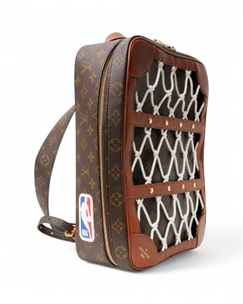 Le sac à dos emblématique de Louis Vuitton, modèle Limited Edition Shoes Box, fruit d'une collaboration exclusive avec la NBA. Fabriqué en toile marron avec le motif classique du monogramme, avec des inserts en cuir et des ferrures dorées. Equipé