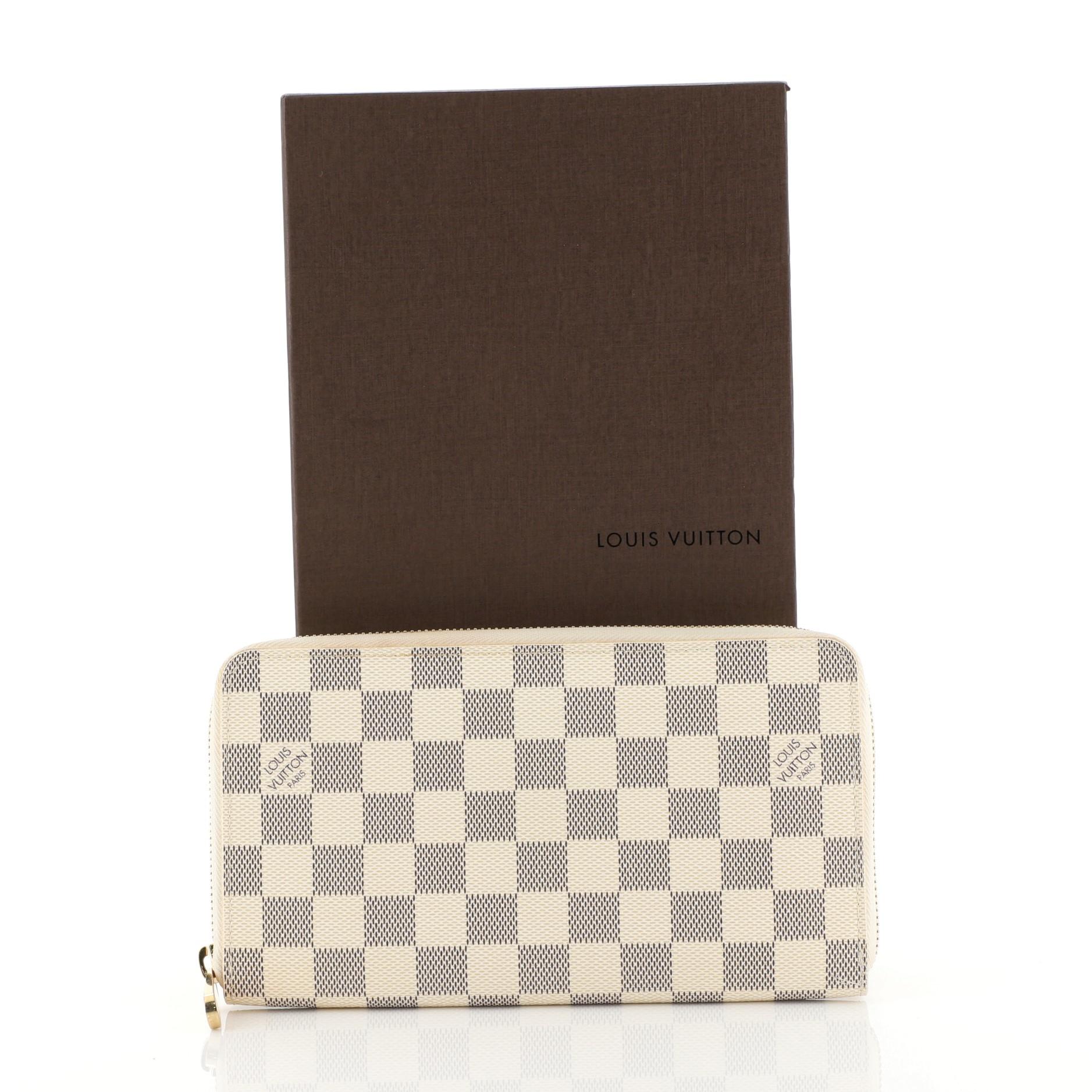 This Louis Vuitton Zippy Organizer Damier, crafted in damier ebene coated canvas, features gold-tone hardware. Its zip around closure opens to a neutral leather interior with multiple card slots, zip compartment, and slip pocket. Authenticity code