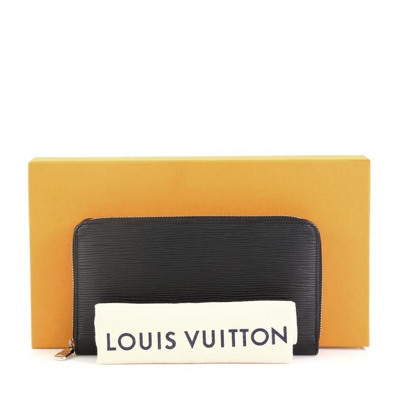 This Louis Vuitton Zippy Organizer Epi Leather, crafted in black electric epi leather, features a zip around closure and silver-tone hardware. Its zip closure opens to a black leather interior with multiple card holders, zip compartment, and patch