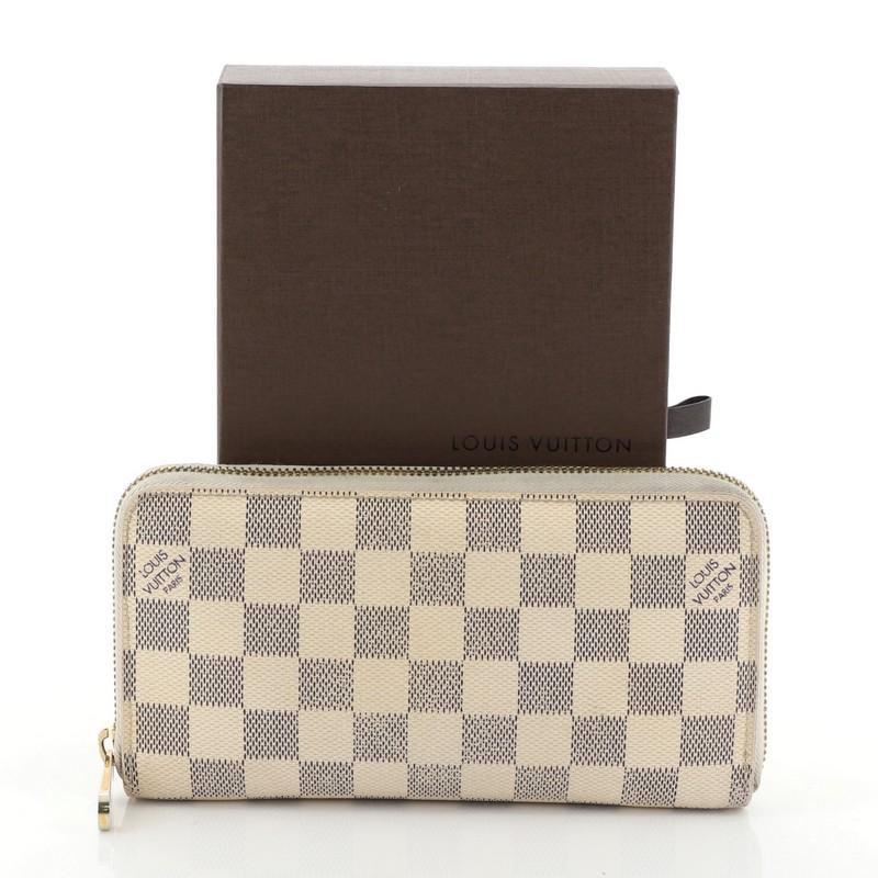 This Louis Vuitton Zippy Wallet Damier, crafted from damier azur coated canvas, features gold-tone hardware. Its all-around zip closure opens to a white leather interior with multiple card slots, two gusseted open pockets, and zip pocket.