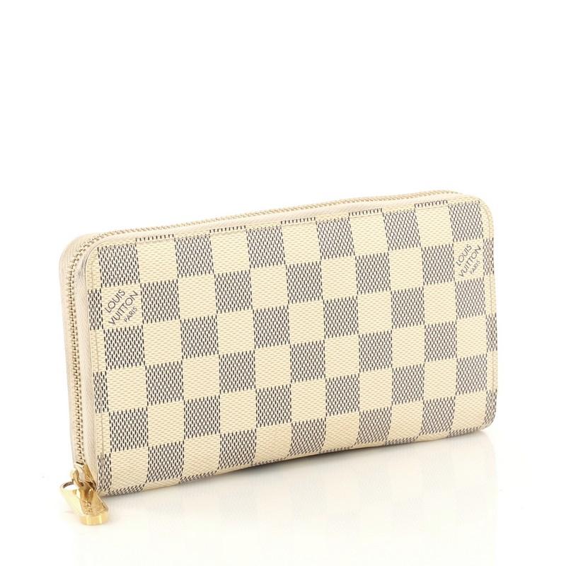 This Louis Vuitton Zippy Wallet Damier, crafted from damier azur coated canvas, features gold-tone hardware. Its all-around zip closure opens to a beige leather interior with multiple card slots, two gusseted open pockets, and zip pocket.