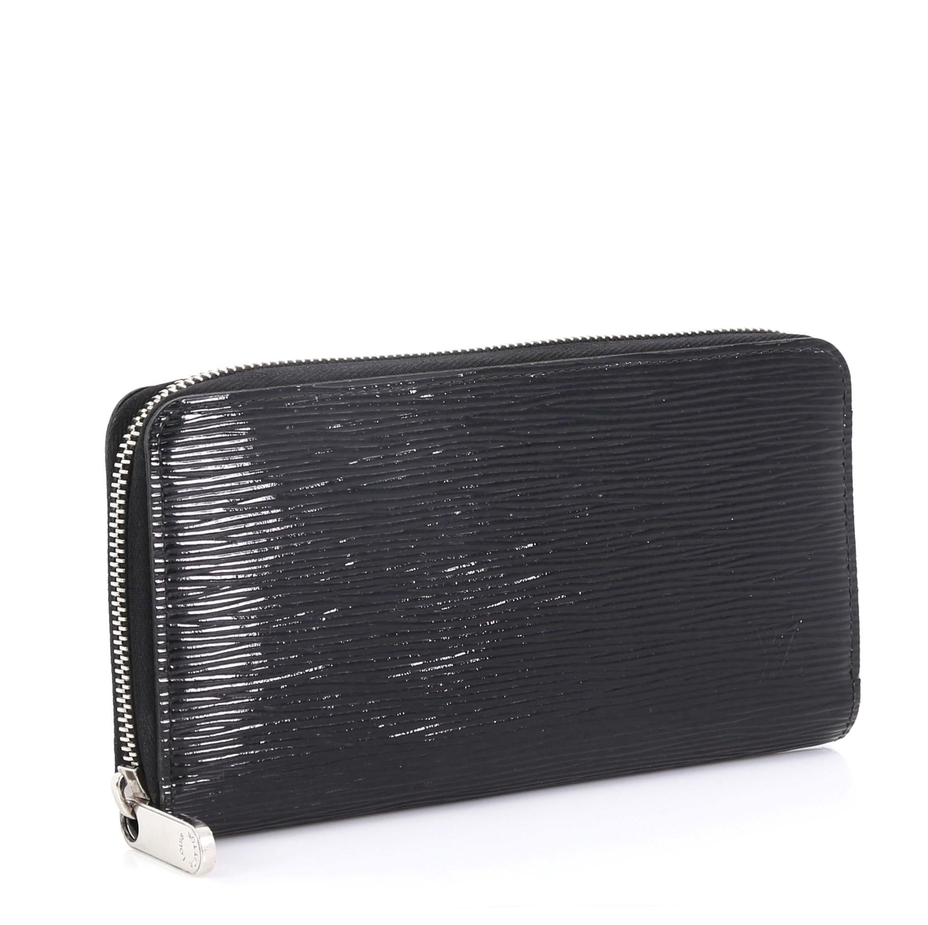 This Louis Vuitton Zippy Wallet Electric Epi Leather, crafted from black electric epi leather, features subtle stamped LV logo and silver-tone hardware. Its zip around closure opens to a black leather interior with middle zip compartment, multiple
