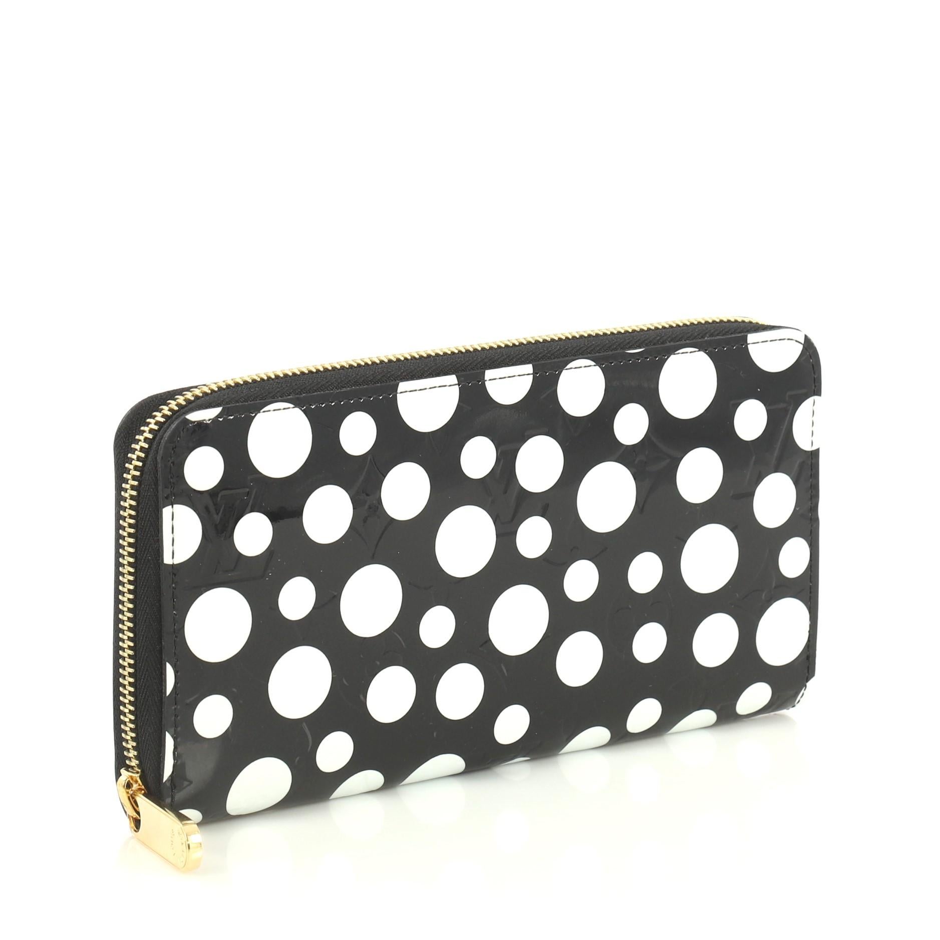 This Louis Vuitton Zippy Wallet Kusama Infinity Dots Monogram Vernis, crafted from black monogram vernis with an overlay of graphic polka dots print, features gold-tone hardware. Its all-around zip closure opens to a black leather interior with