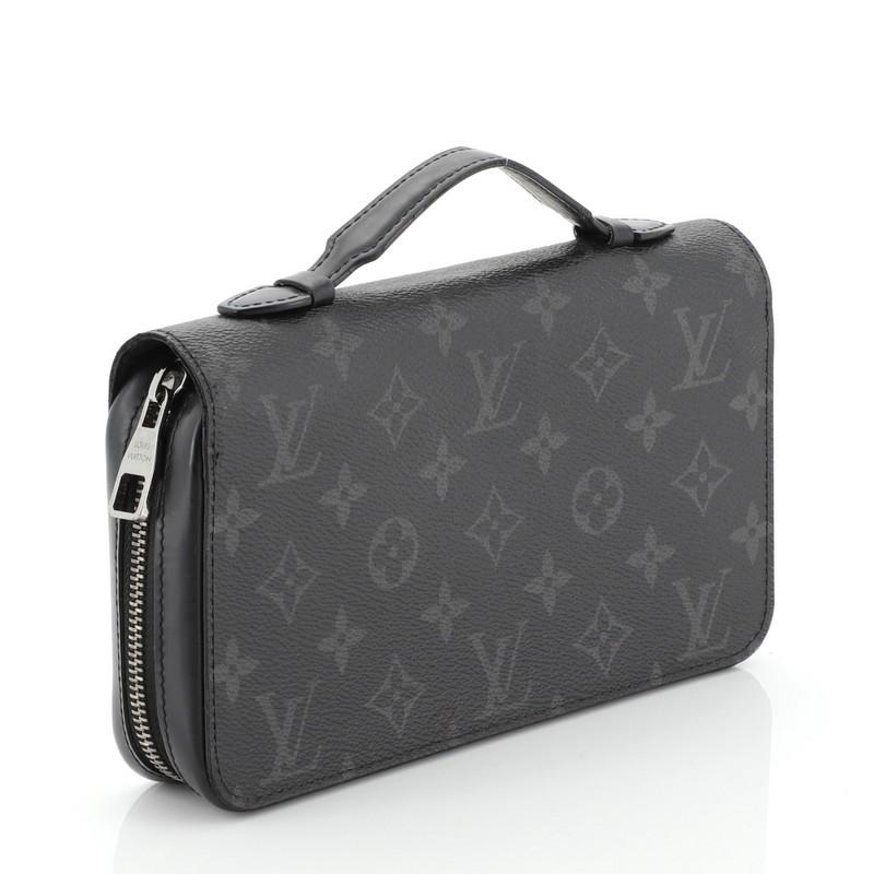 This Louis Vuitton Zippy Wallet Monogram Eclipse Canvas XL, crafted in black monogram eclipse coated canvas, features a leather handle and silver-tone hardware. Its zip closure opens to a black leather interior with multiple card slots, zip