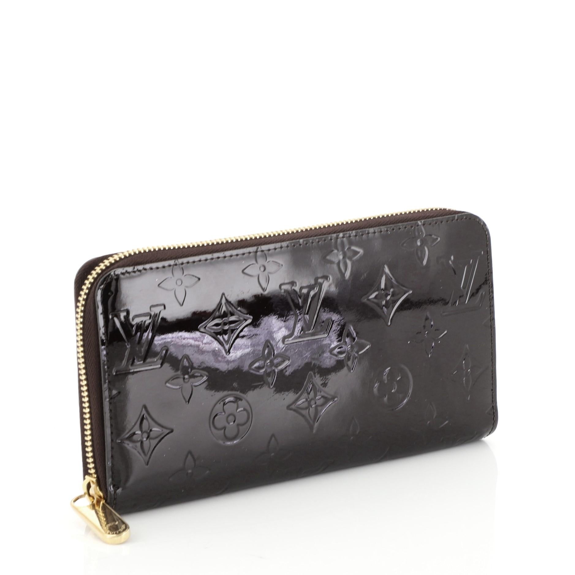 This Louis Vuitton Zippy Wallet Monogram Vernis, crafted in purple monogram vernis, features gold-tone hardware. Its all-around zip closure opens to a purple leather interior with a middle zip compartment, slip pocket, and multiple card slots.