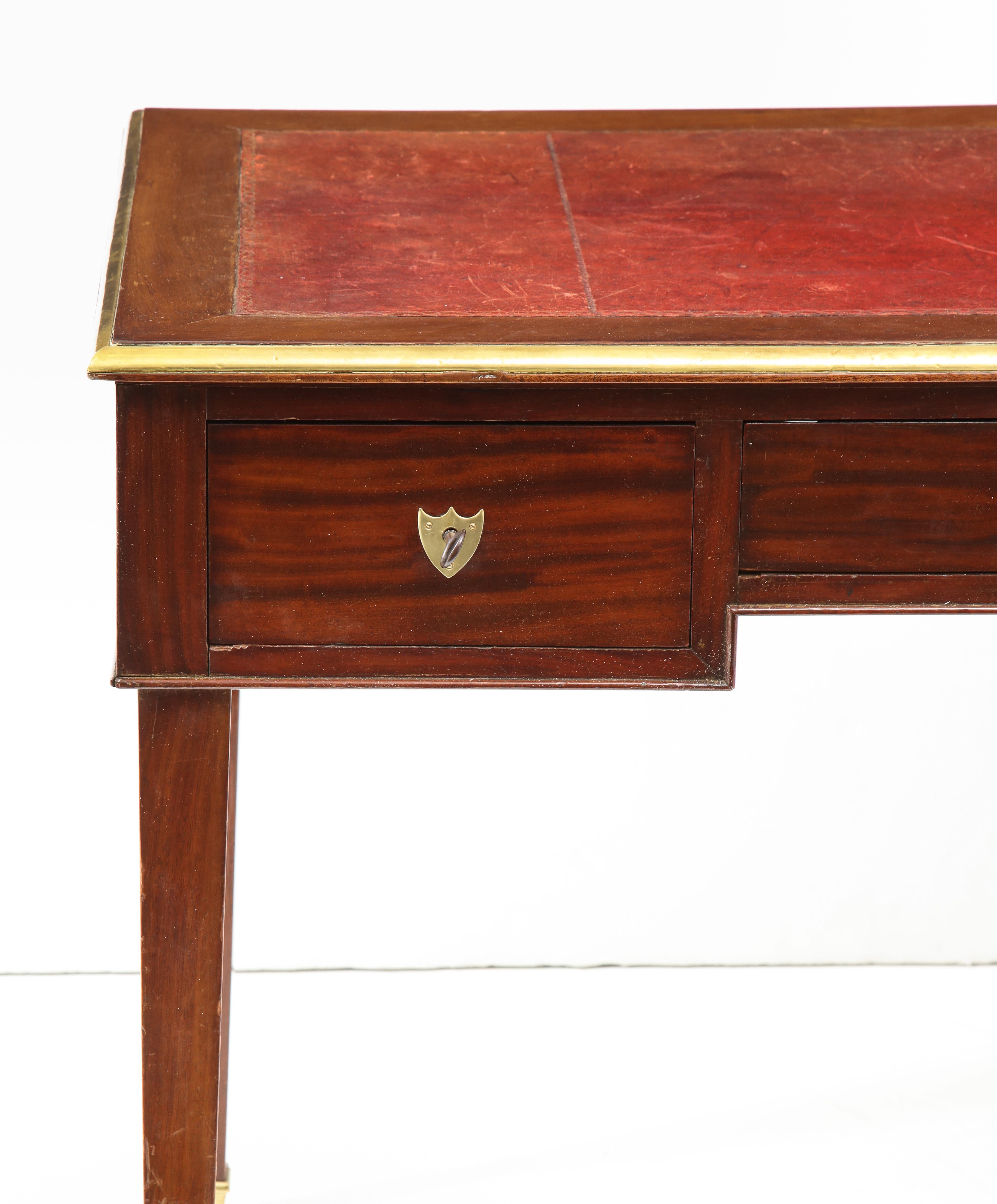 Despite its clean, simple lines, this Louis XVI period bureau plat has real star power. In mahogany with brass detailing and a red leather top, the finish has warn to a lovely warm patina. The writing table features three drawers, with shield key