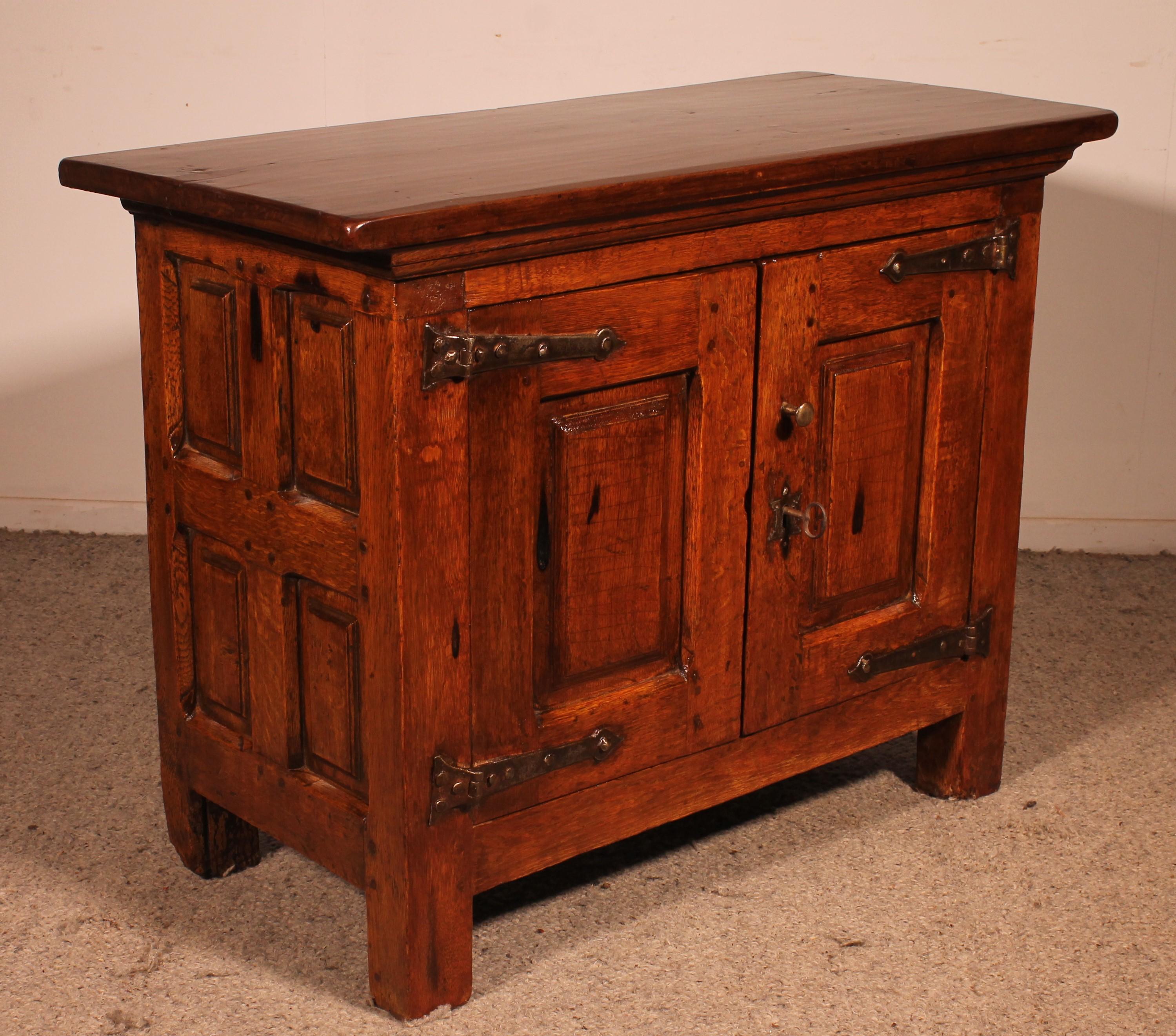 small 2 door buffet or cupboard in oak and walnut from the 17th century from Spain

small unusual model with very beautiful carved panels as well as paneled sides.

It has its original lock and key
Very beautiful irons on the two doors typical of