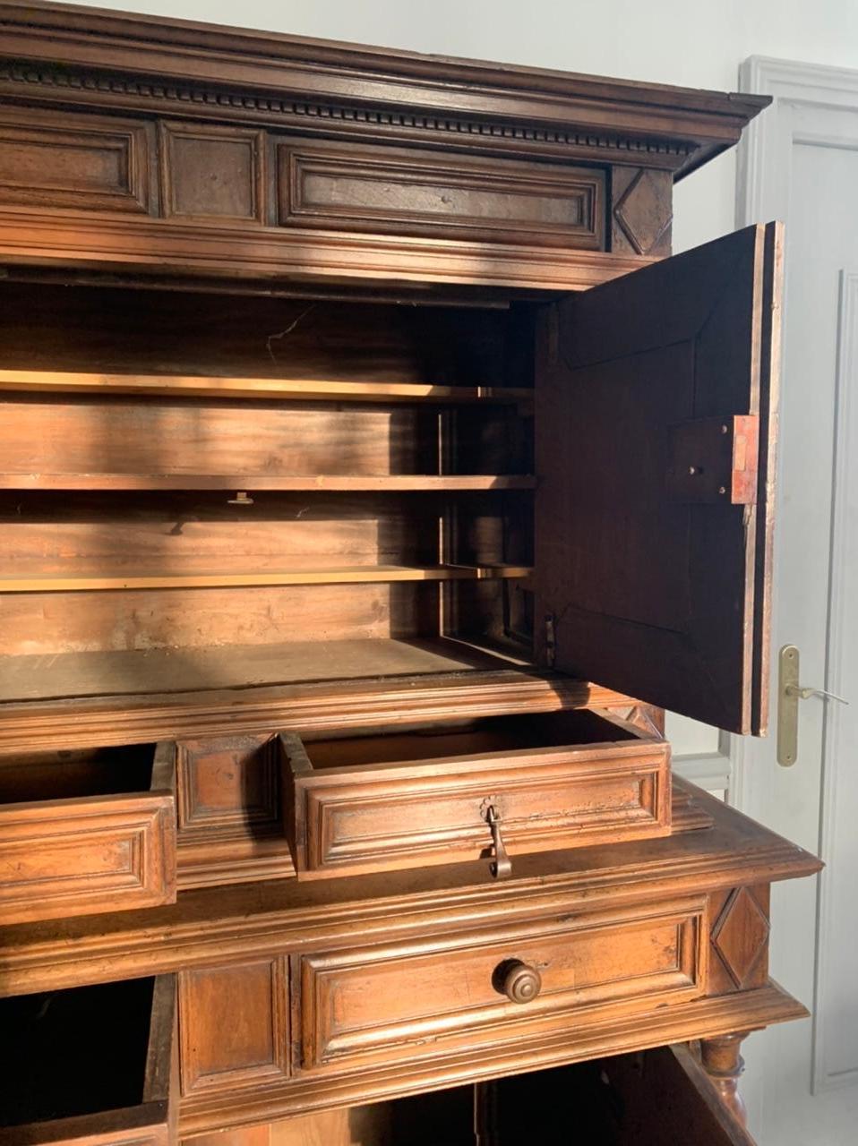 Piccolo buffet francese a due corpi del XVII secolo. Questo antico mobile in legno di noce intagliato del periodo Luigi XIII ha quattro ante, quattro cassetti ed è decorato con rombi e colonne tortili. Il set poggia su piedini a sfera. 
Francia