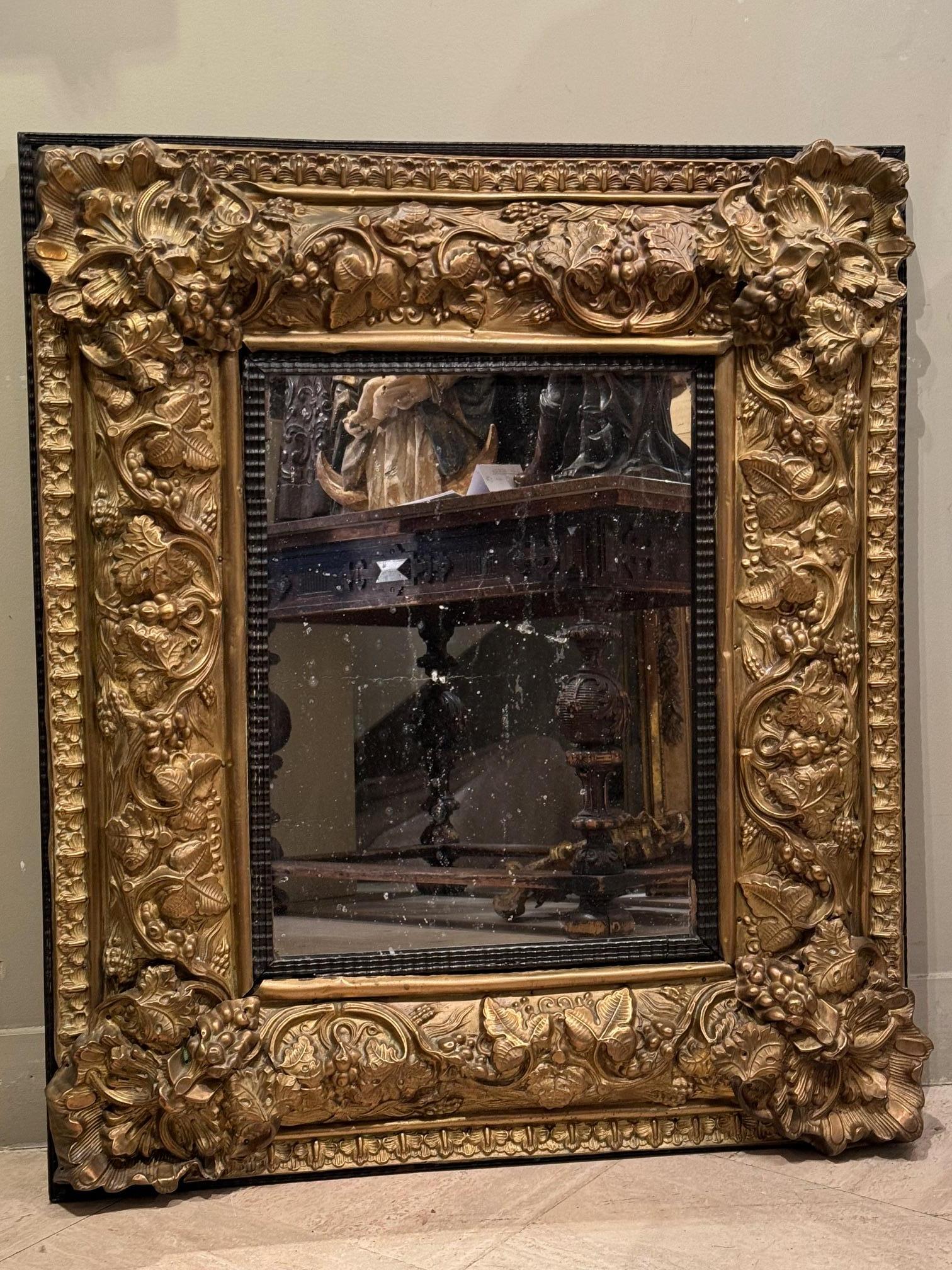 Specchio in rame dorato o in foglia di ottone con decorazione in rilievo di tralci di vite. 
L'interno e l'esterno sono incorniciati da strisce arabescate. Vetro di mercurio centrale, forse originale. 
Stile Luigi XIII realizzato sotto Napoleone