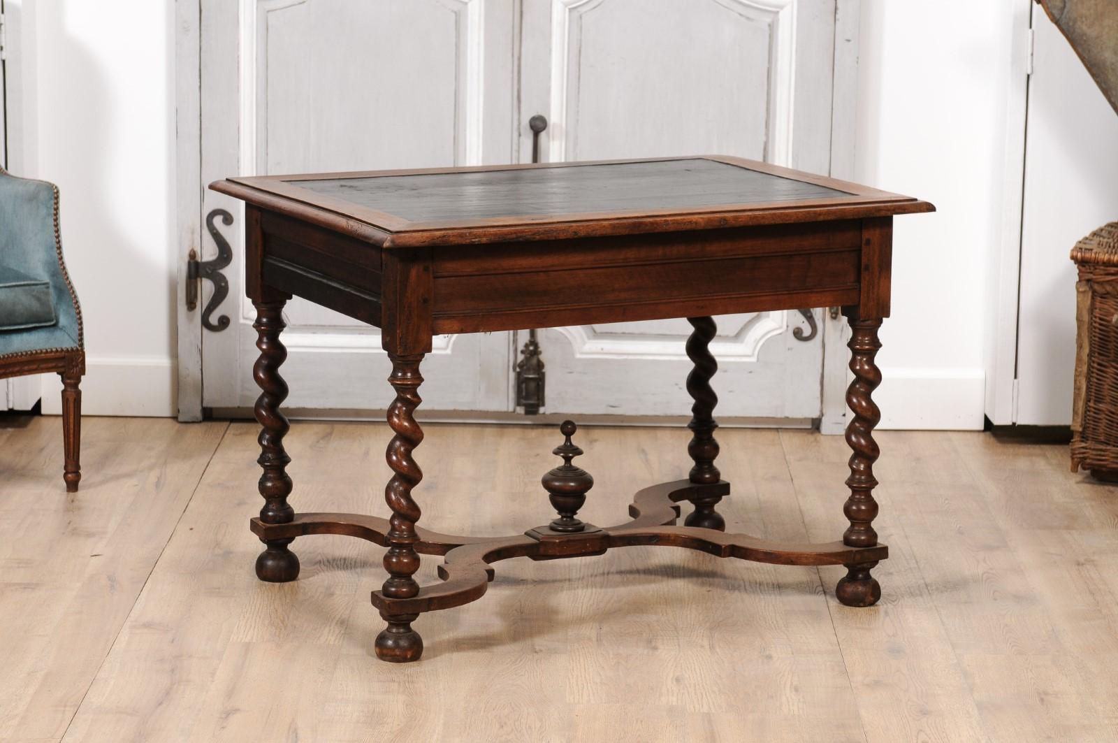 A French Louis XIII period walnut writing table from circa 1630 with two lateral drawers, barley twist base, black painted top and carved X-Form cross stretcher accented with central finial. Lose yourself in the grandeur of French history with this