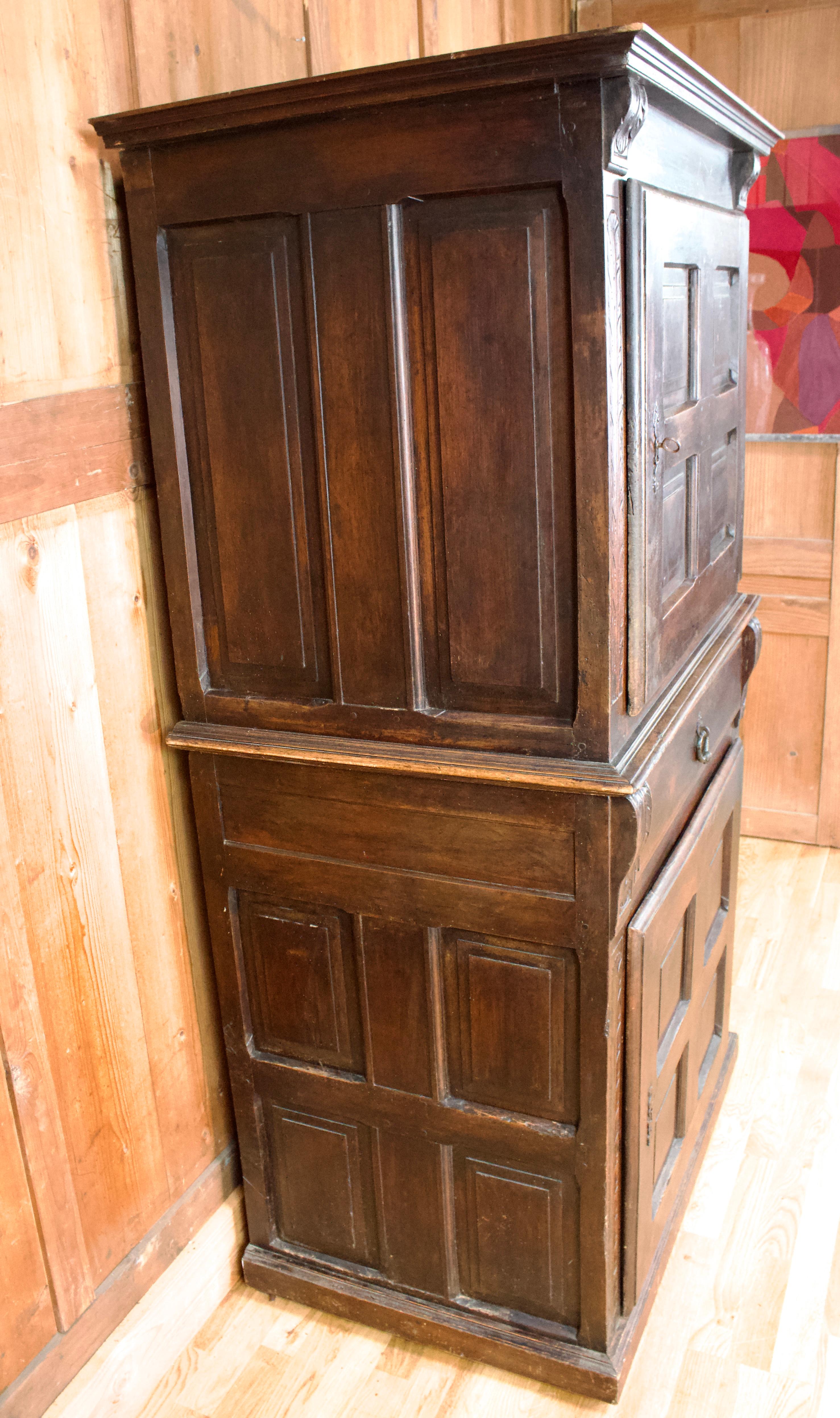 Cabinet d'époque Louis XIII, en bois sculpté, ouvrant à quatre portes à panneaux et un tiroir dans la partie centrale, celui-ci avec une très belle poignée en métal ciselé. Les montants du meuble sont décorés de motifs végétaux et se terminent dans