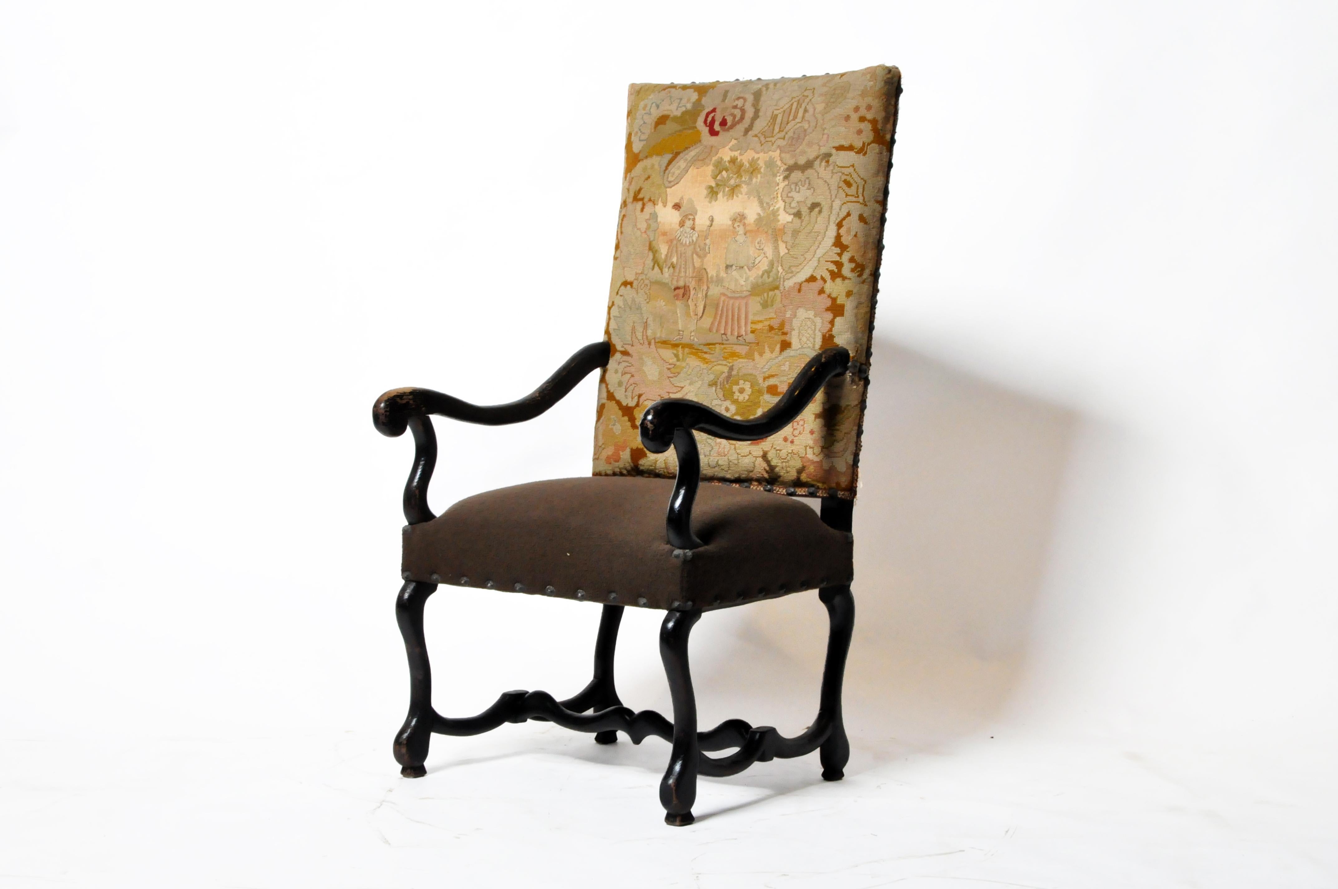 This impressive French arm chair chair is carved from walnut and features an upholstered antique tapestry back and boiled wool seat. The original seat cushion stuffing has been supplemented by contemporary materials. The arms and legs have been