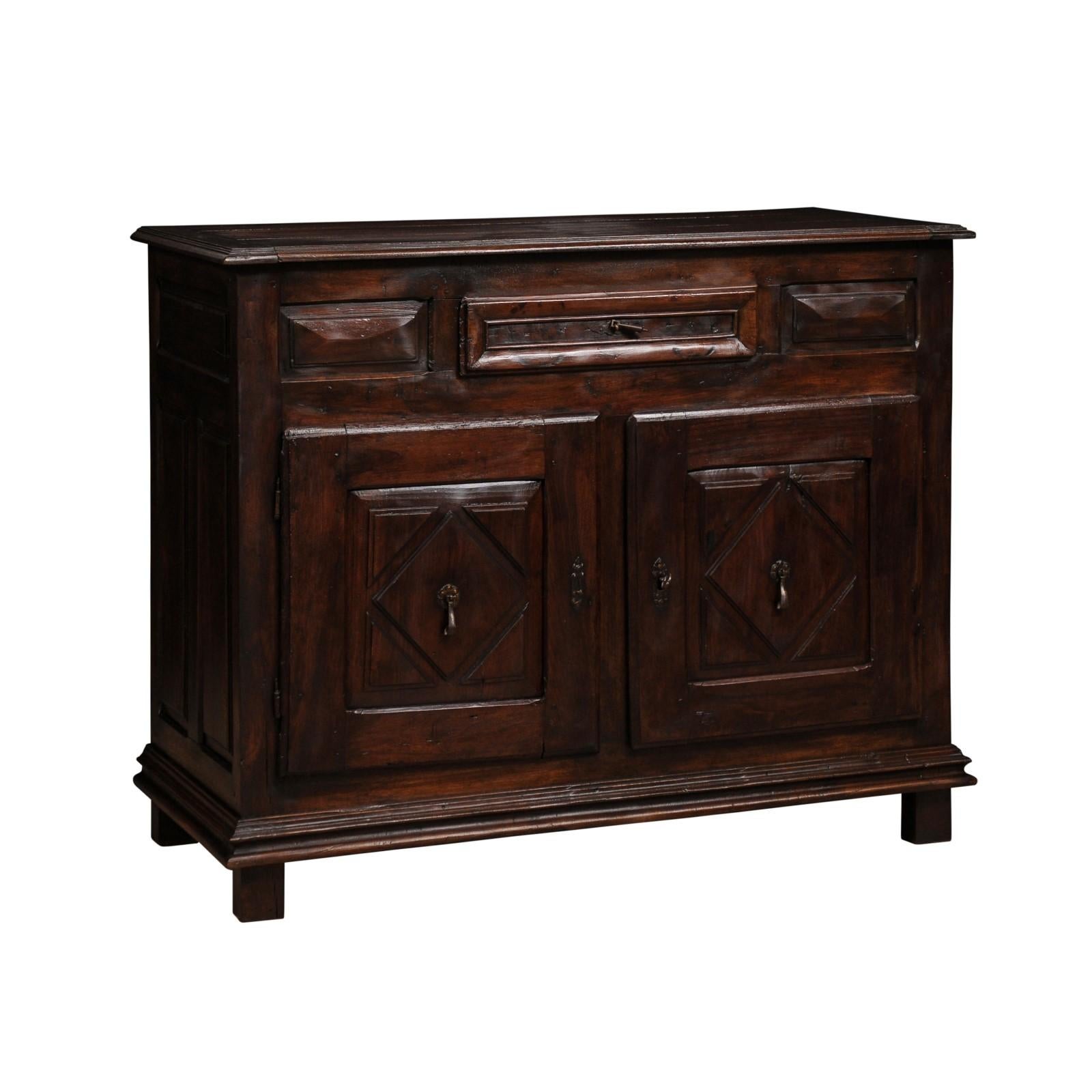A French Louis XIII style walnut buffet from the 19th century with two doors, single drawer and carved diamond motifs. Showcasing the elegance of French design, this Louis XIII style walnut buffet, dating from the 19th century, gracefully captures