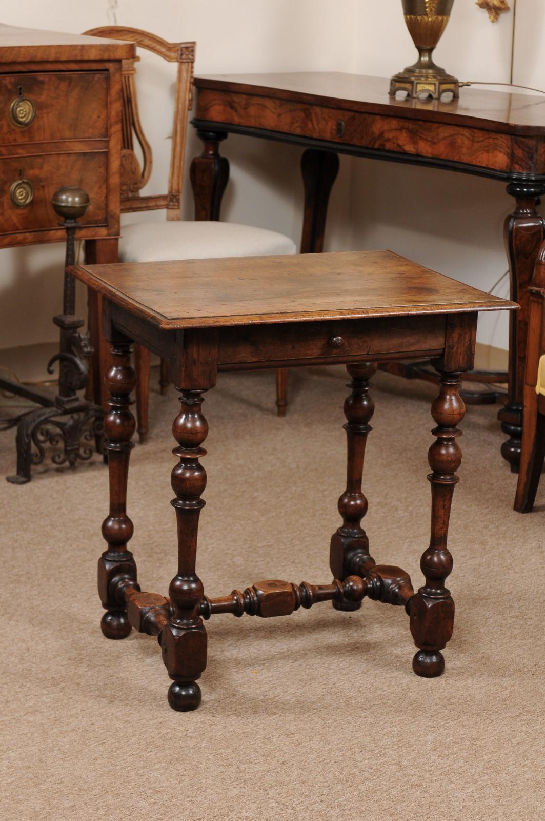 A Louis XIII style French walnut side table with drawer, turned legs joined by stretcher and ending in bun feet. The table dates from the 18th century.
