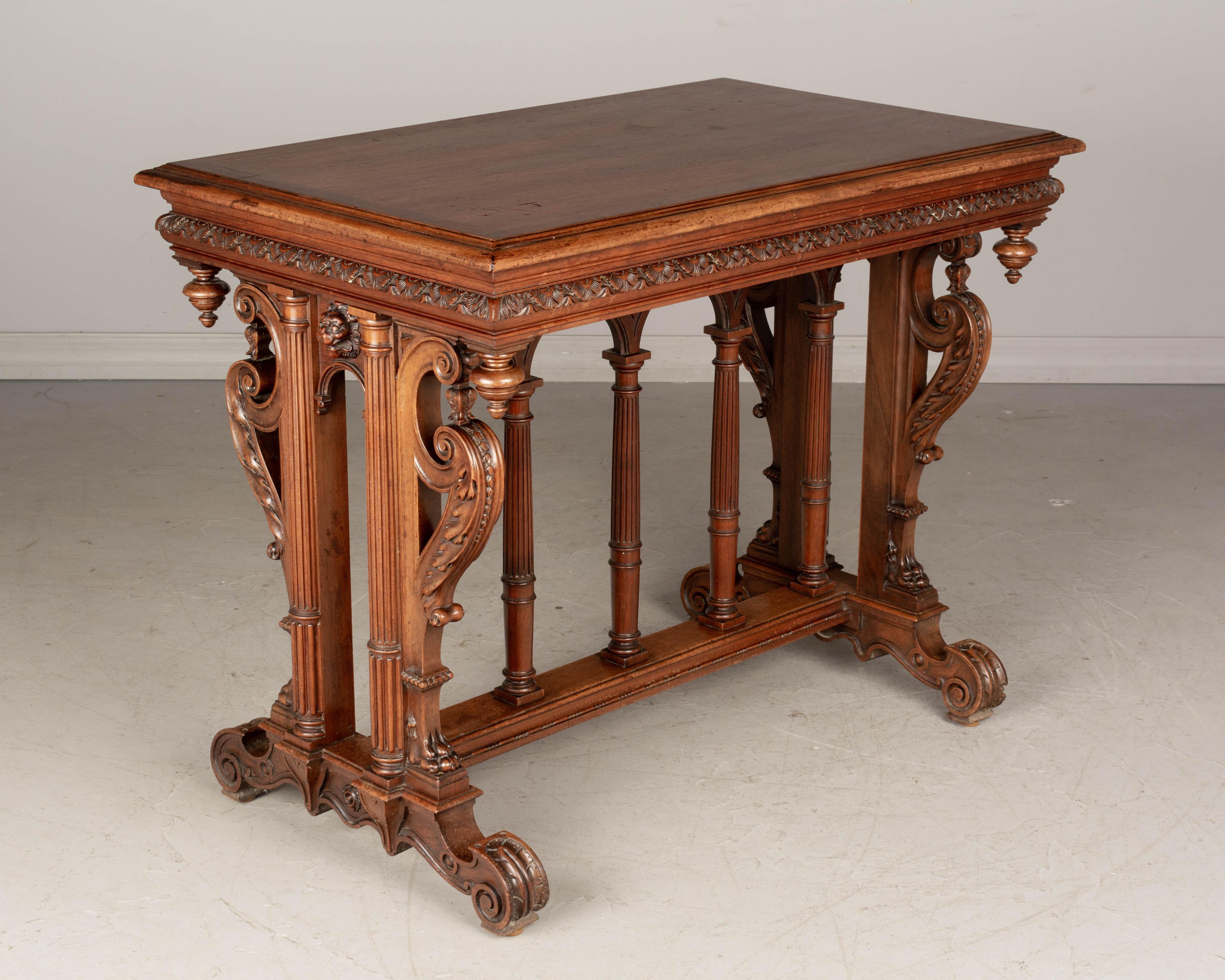 A Louis XIII style French side table made of solid hand-carved walnut. Elaborately detailed in a Neo Renaissance style with fine turned legs forming an arched colonnade over the center stretcher. Fine carvings include large scrolls with acanthus
