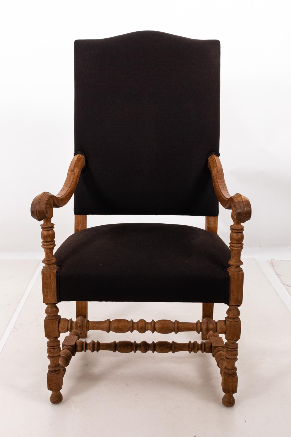 Louis XIII style upholstered armchair with bleached oak frame and black Belgian linen, circa mid-20th century. The piece also features scrolled arms and ball-and-ring turned legs. Please note of wear consistent with age.
