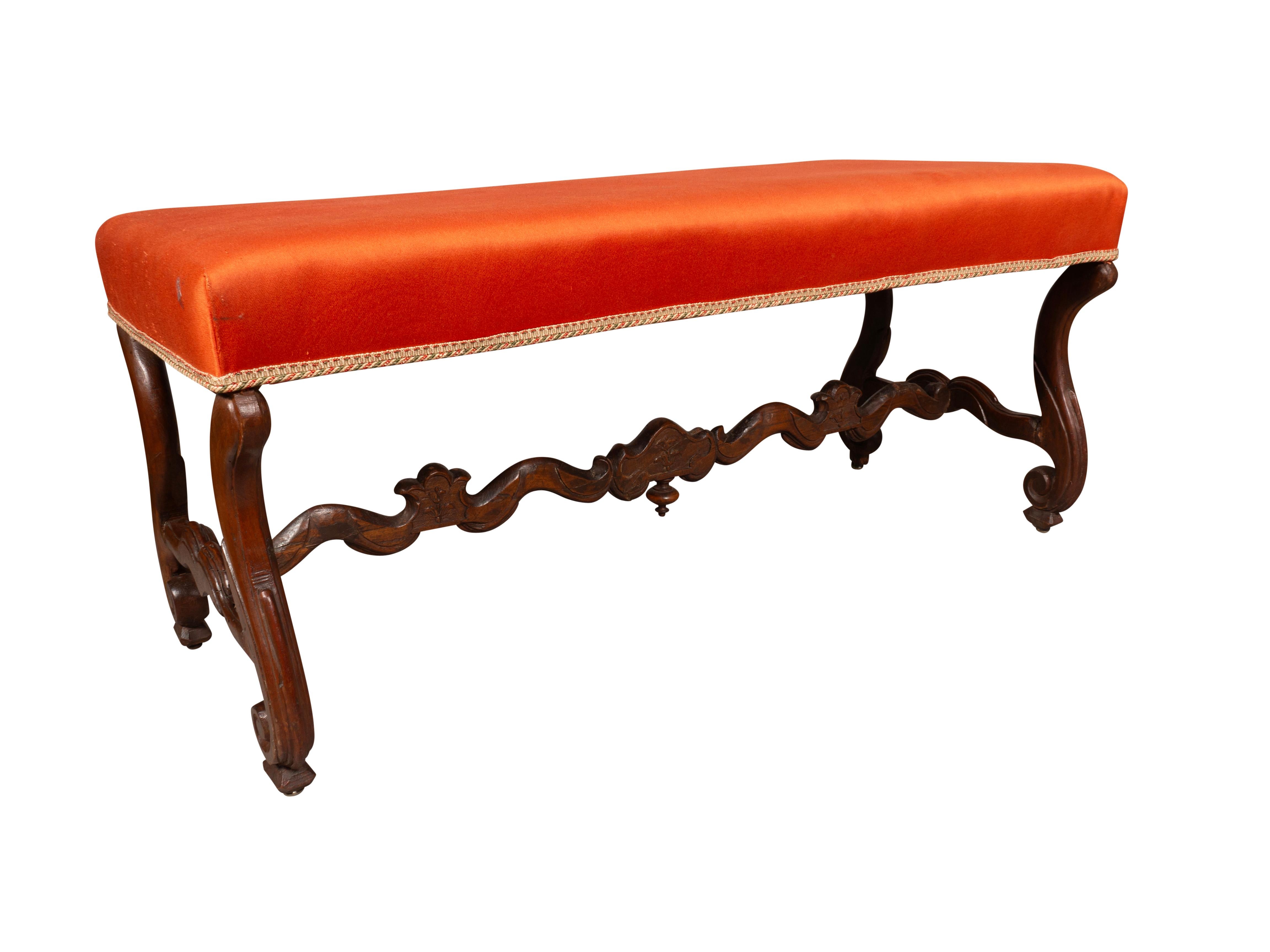 With old red upholstery and carved curved legs joined by a conforming stretcher.