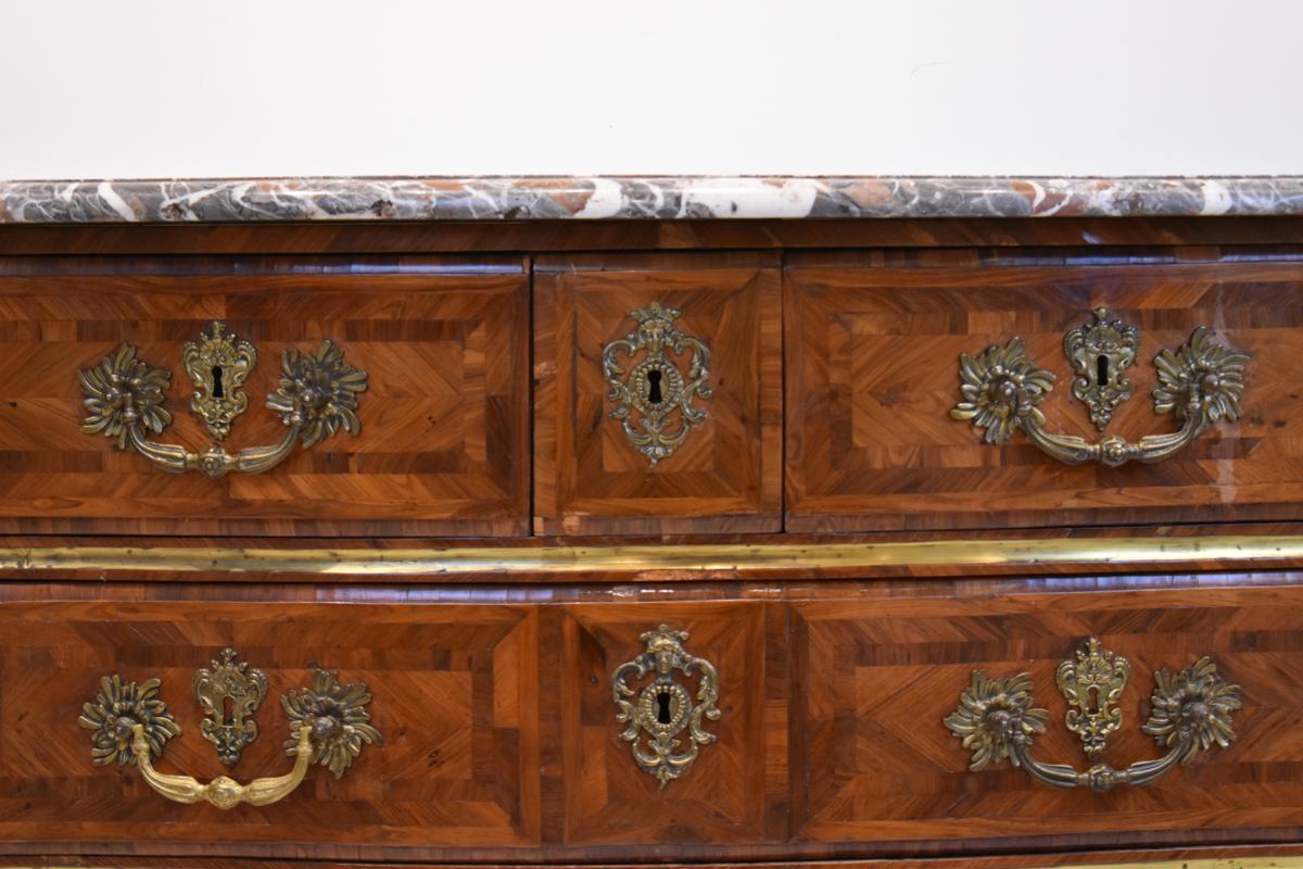 Questo squisito cassettone Luigi XIV del XVIII secolo è un perfetto esempio dell'opulenza e della grandezza associate al regno del Re Sole. La cassapanca presenta un ricco intarsio di varie impiallacciature di legno, che mette in mostra