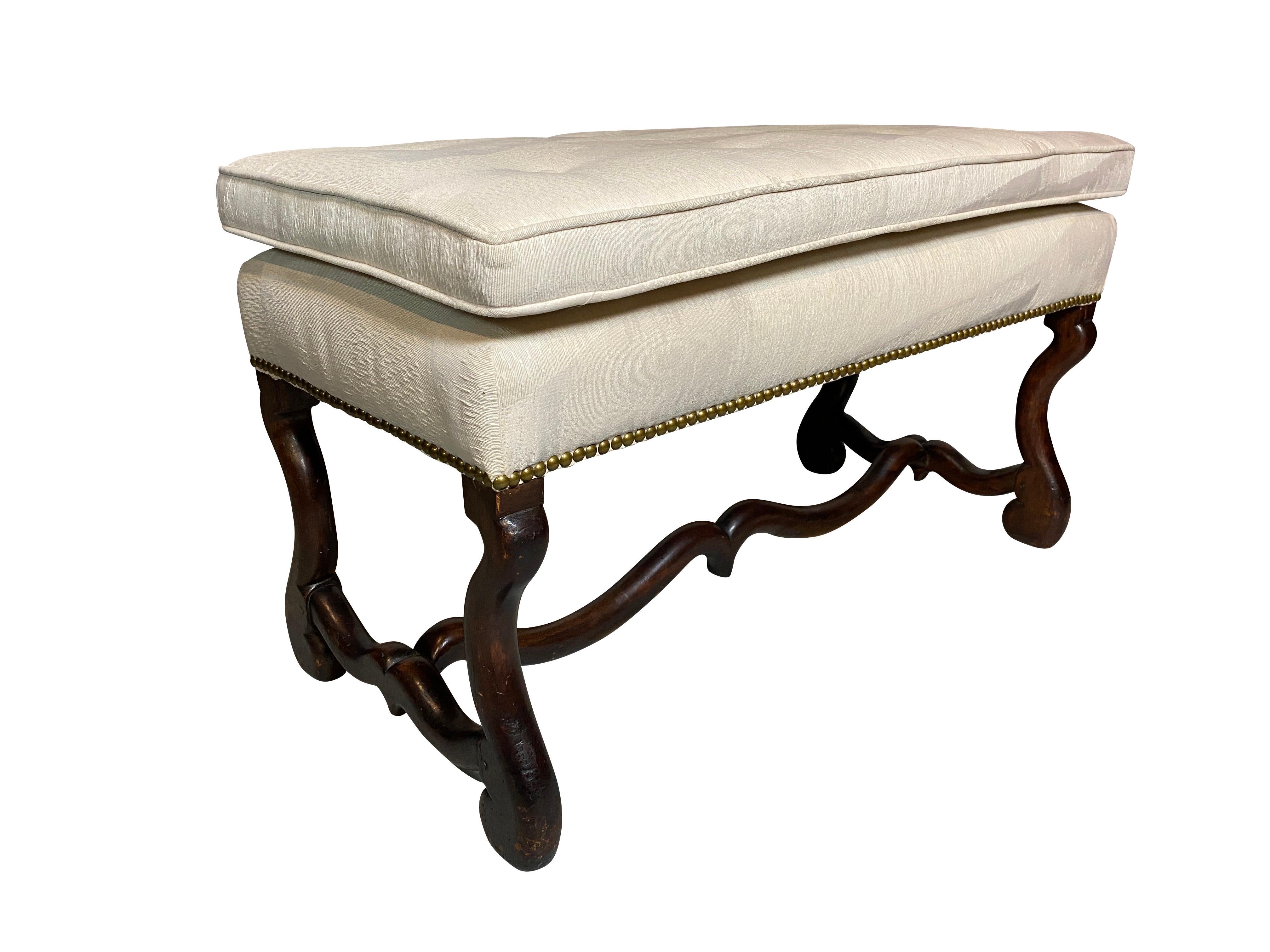 Rectangular upholstered seat raised on curved legs joined by a curved stretcher.