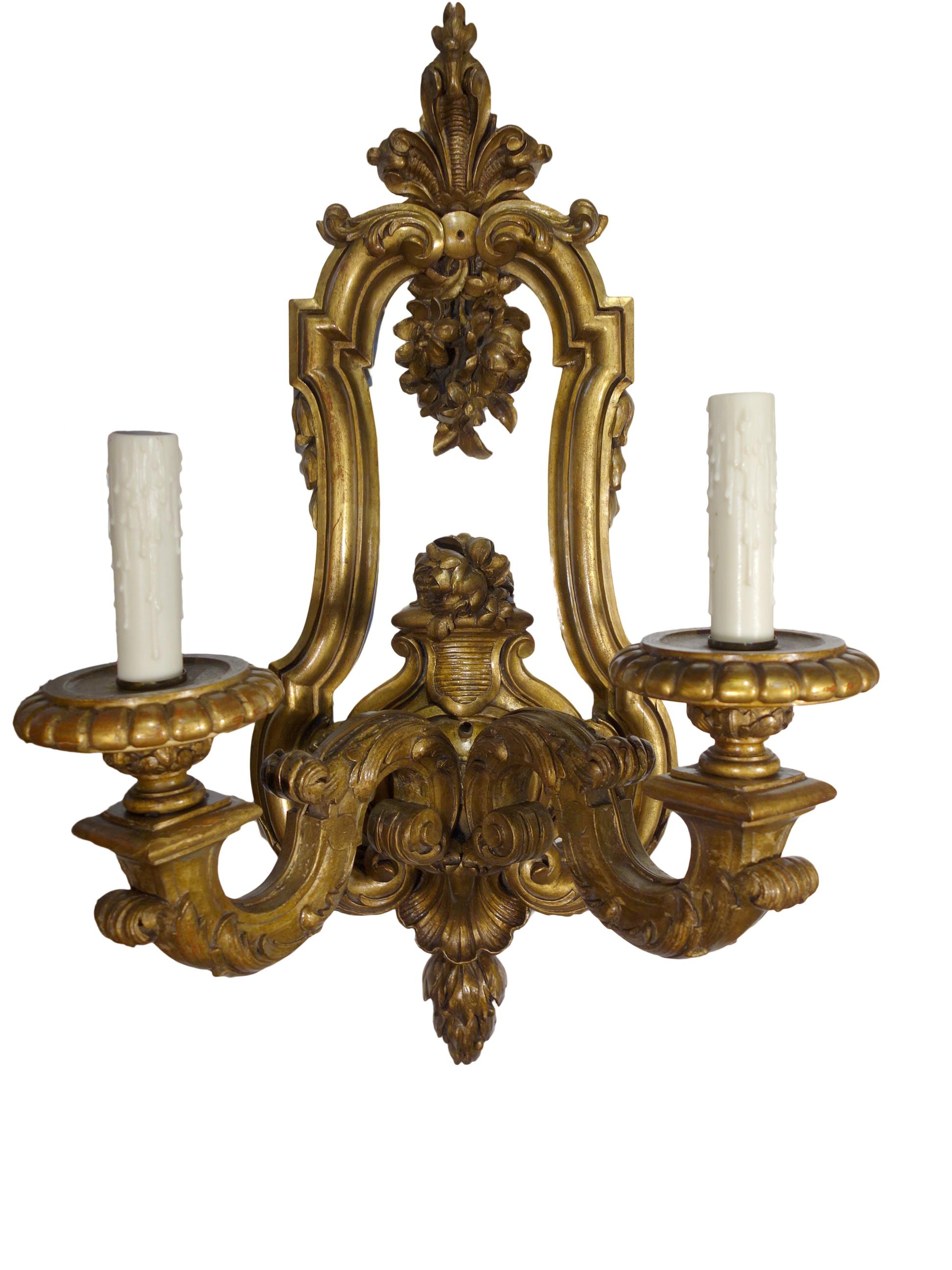 Louis XIV Baroque style giltwood 2-light sconce pair. Fine Italian reproduction, grande scale,  these sconce pieces are hand carved and ornately detailed, circa 1930. Professionally rewired and restored, standard base bulb sockets. Sotheby's New