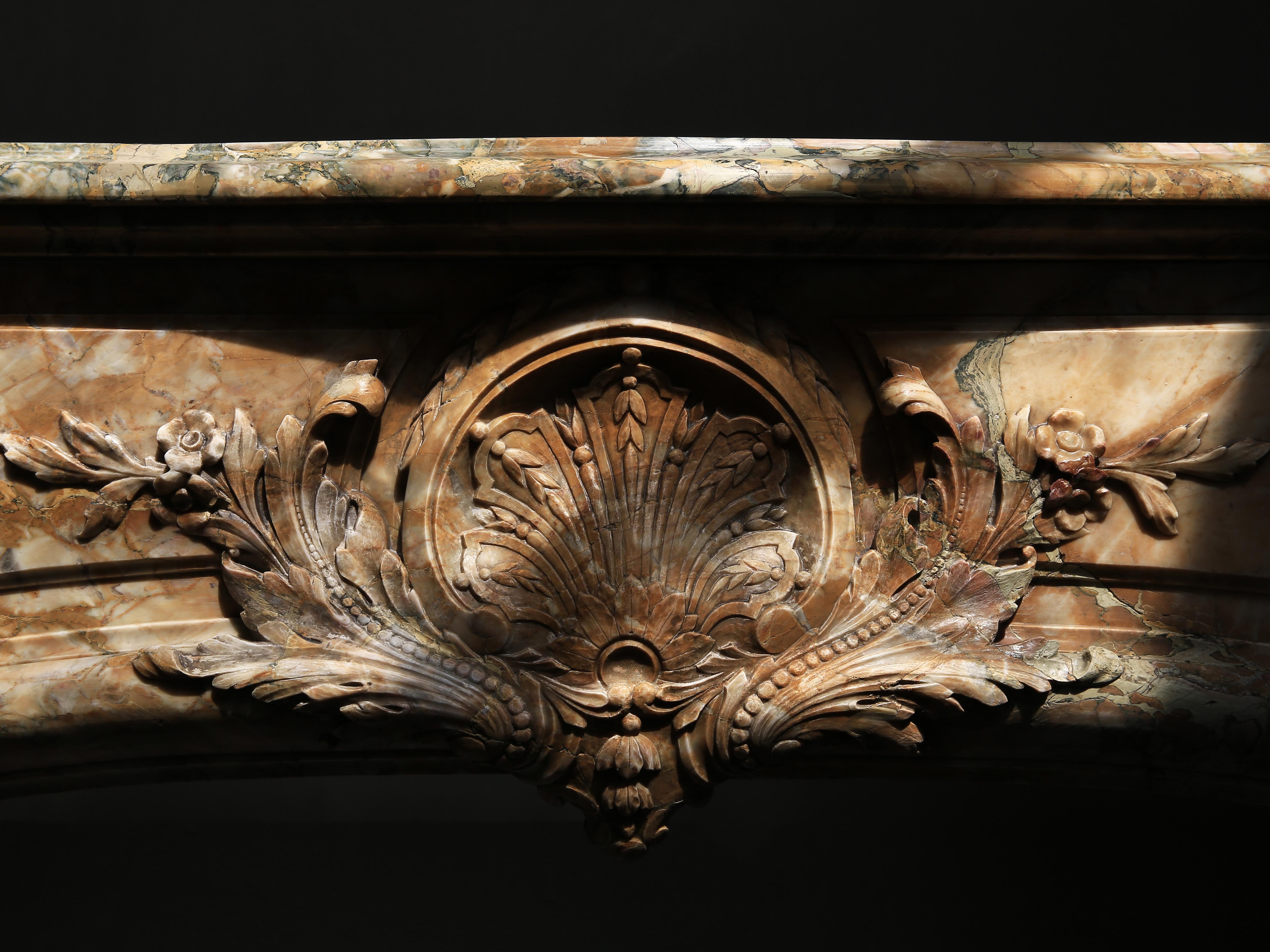 Beautiful antique fireplace of Brocatelle de Sienna marble, circa 1830-1850! This mantel is in the style of Louis XIV Boudin and comes from a Classic apartment in Paris. The mantel (fireplace) is richly sculpted with ornaments and embellishments