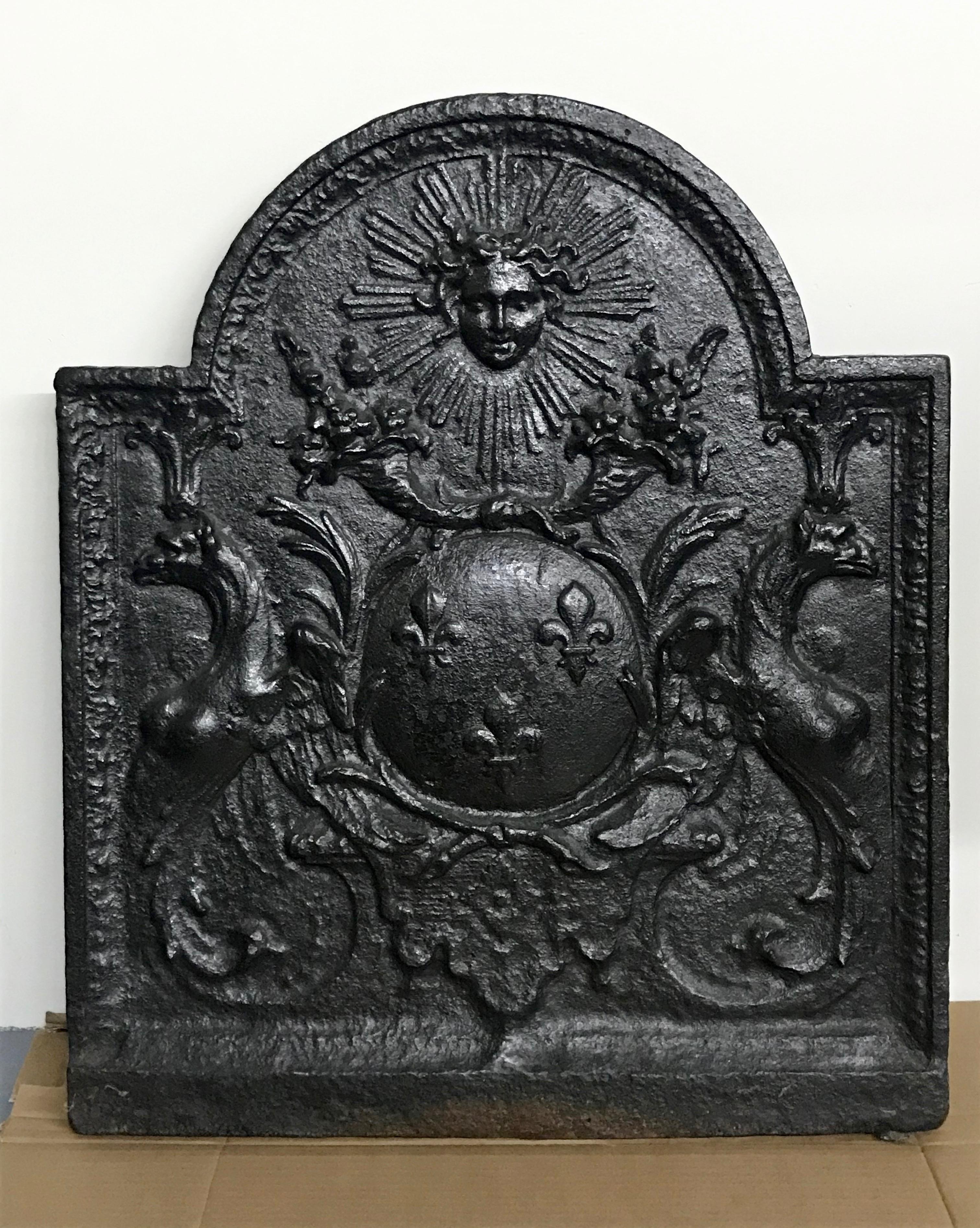 Very nice quality and highly decorative French cast iron fireback in the style of Louis XIV, the Sun King, featuring two griffins flanking a heraldic shield of arms with fleurs-de-lis, cornucopias and laurel leaves. 