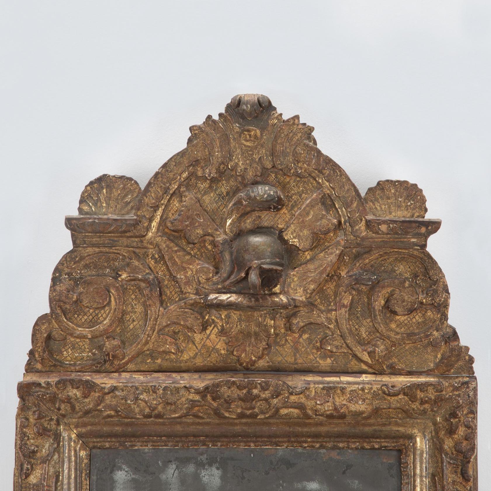A wonderful French early 18th Century Regence giltwood mirror. 

The heavily foxed original mercury glass plate with a soft shallow bevel. The carved frame with foliate strapwork and flowerheads on a fine cross-hatched ground with scrolling foliate