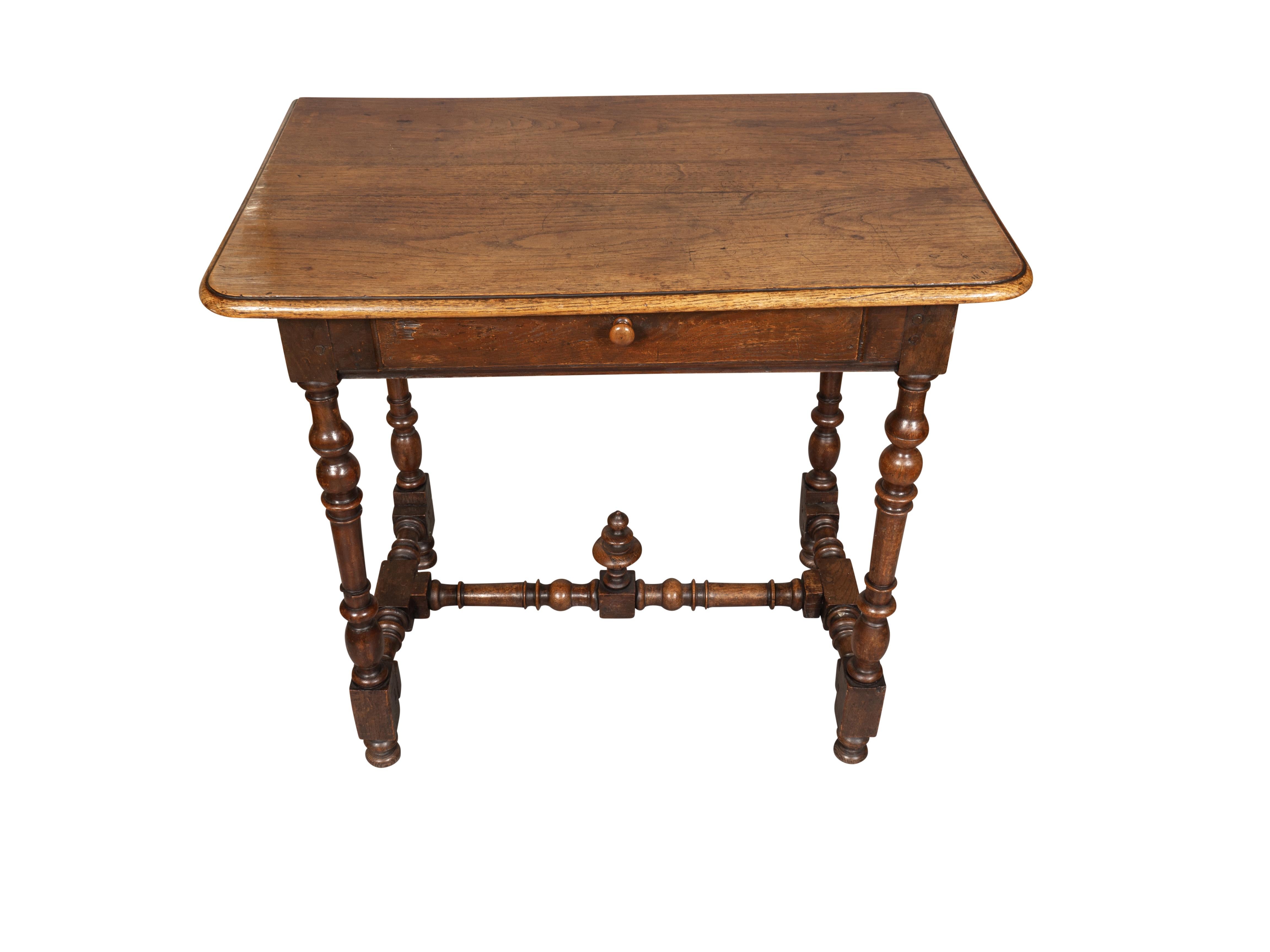Rectangular top over a drawer with wood knob. Raised on turned legs with a conforming turned stretcher.. Bun feet.