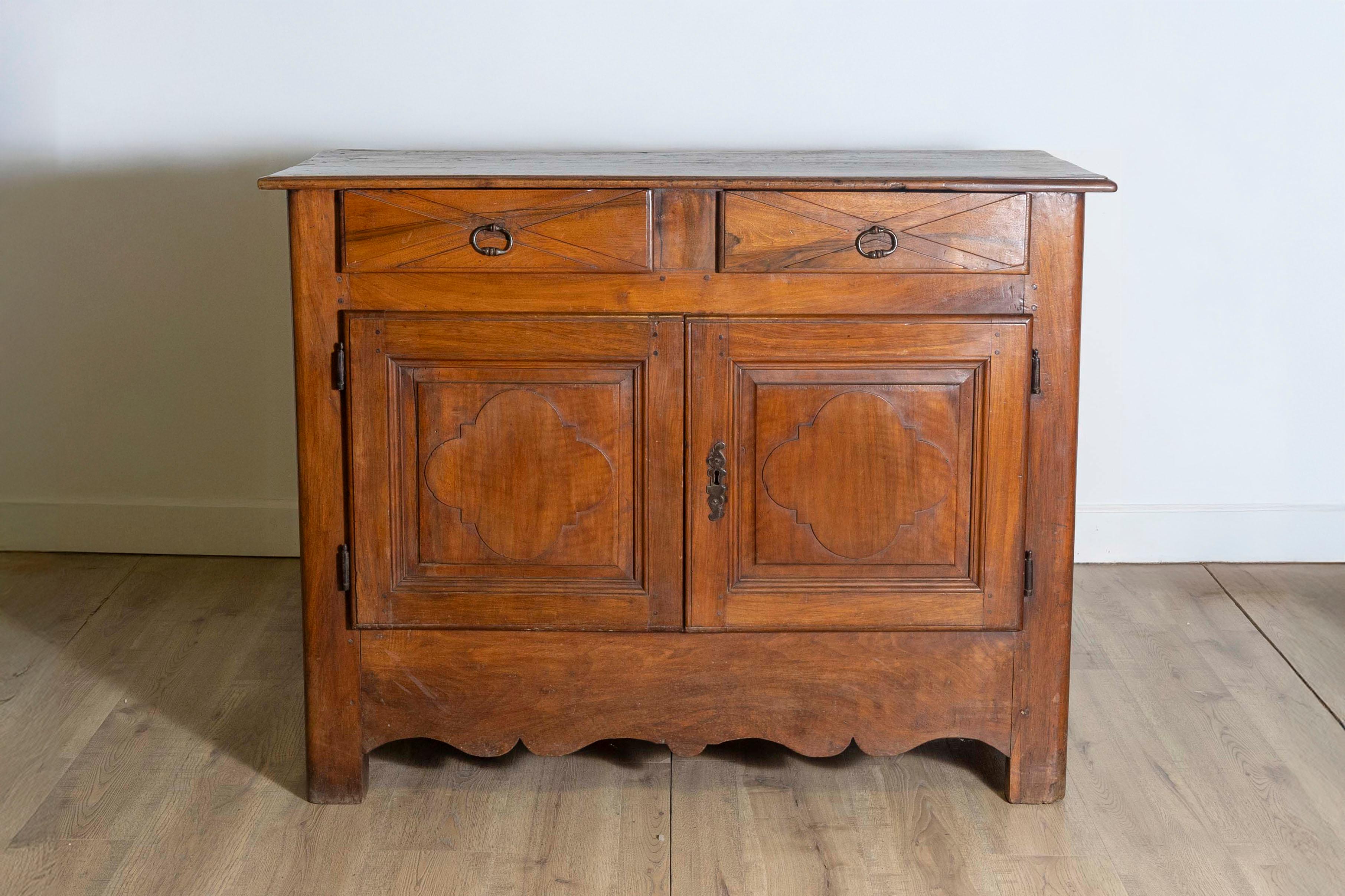 Un buffet francese in noce del XVIII secolo, risalente al periodo Luigi XIV, con due cassetti e due ante, intagliati a forma di X e motivi a trifoglio. Lasciati conquistare dall'eleganza regale di questo buffet in noce del XVIII secolo, un'unione
