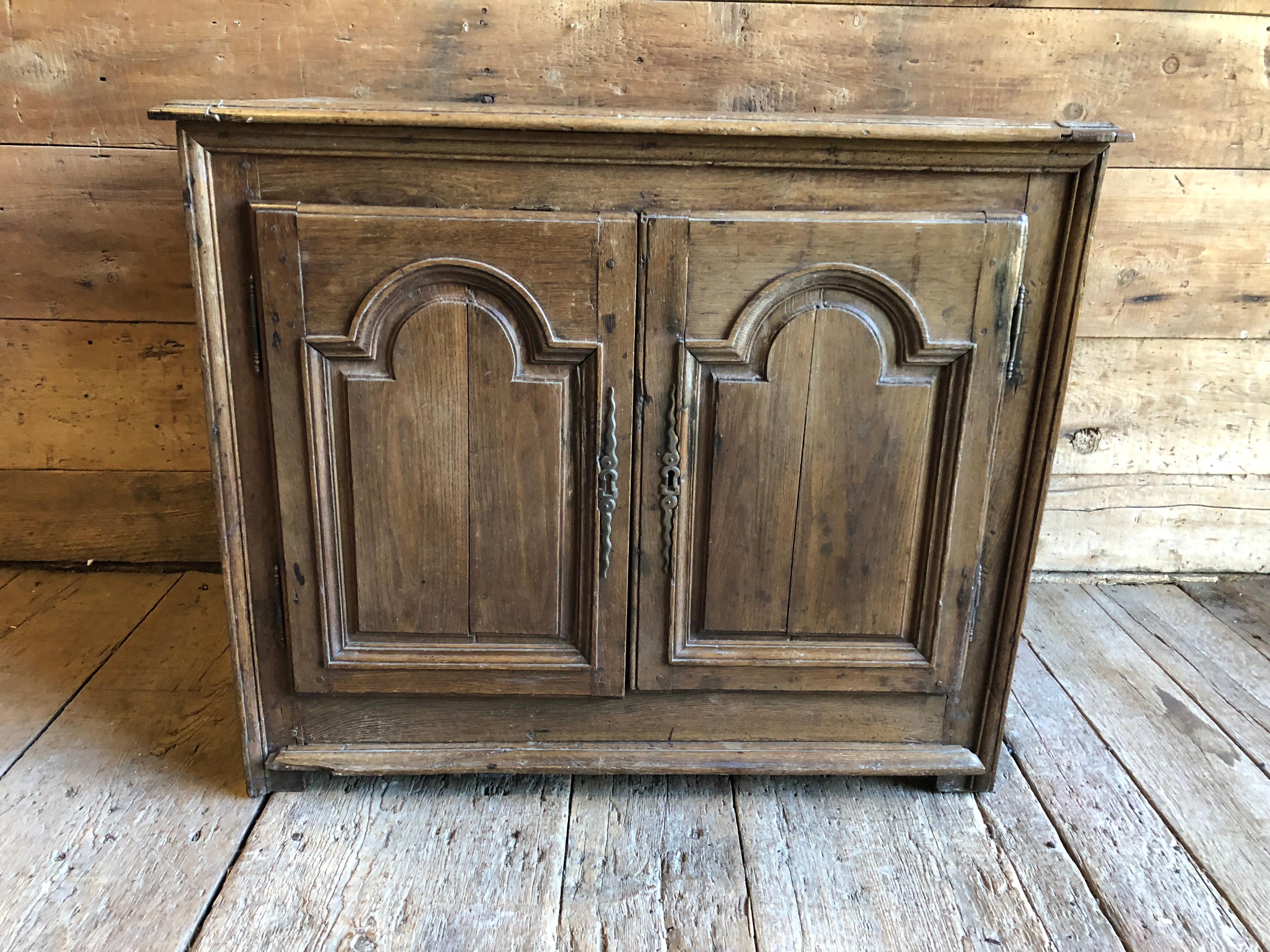 An early to mid-18th century French cabinet in oak, Louis XIV period, with two tombstone panelled doors, original wood top on simple feet. It is a nice size for a bar cabinet or a bathroom vanity.