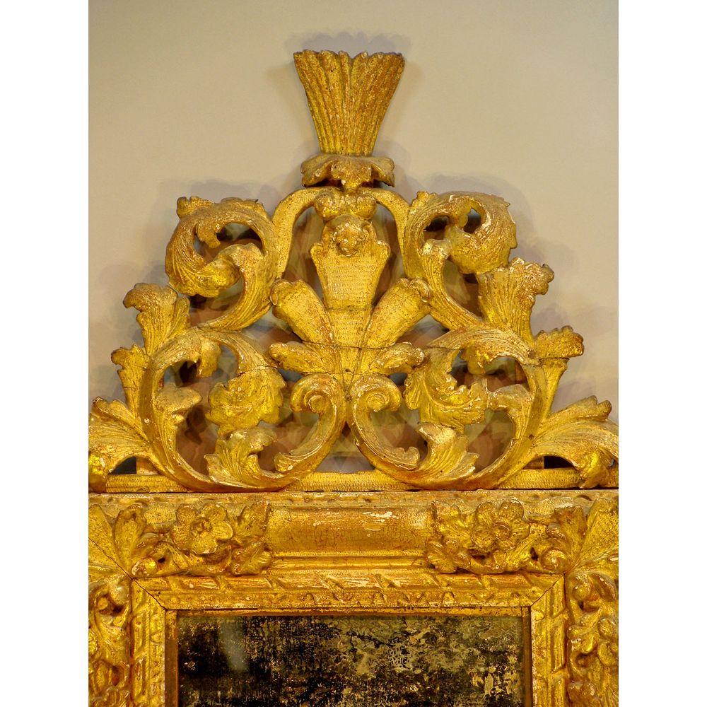 A late 17th century or early 18th century Louis XIV period (1638-1715) carved giltwood mirror.

Apparently retaining the original mirror plate and gilding. 
Well carved with trailing flowers and acanthus, with the original bold cresting. Minor old