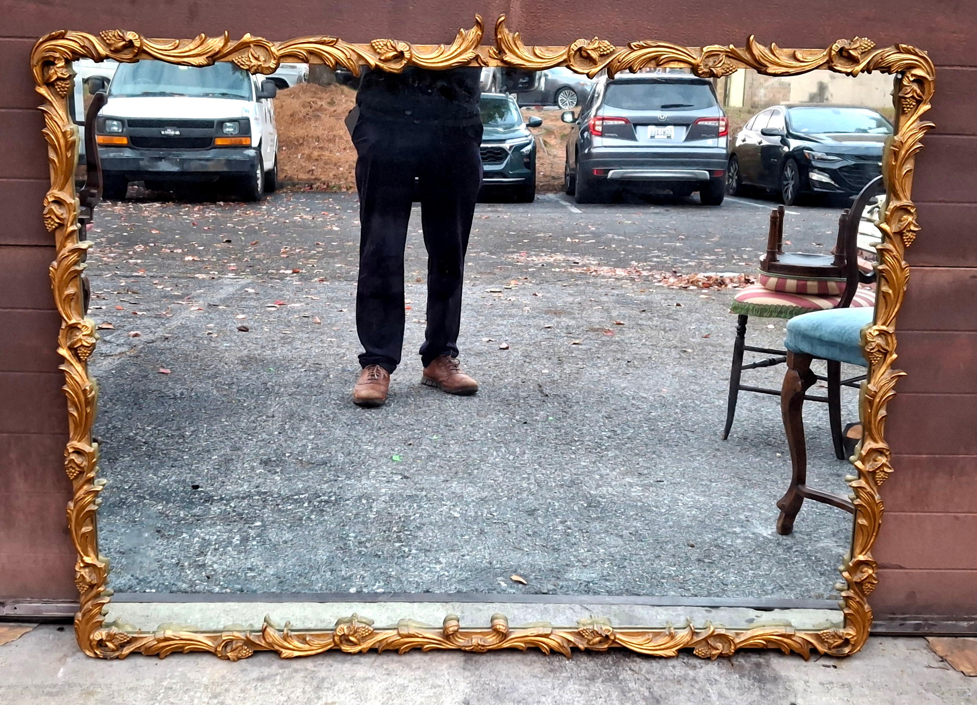 Grand miroir mural de style Louis XIV à cadre en bois sculpté et doré, circa 1920
Dimensions approximatives : 51