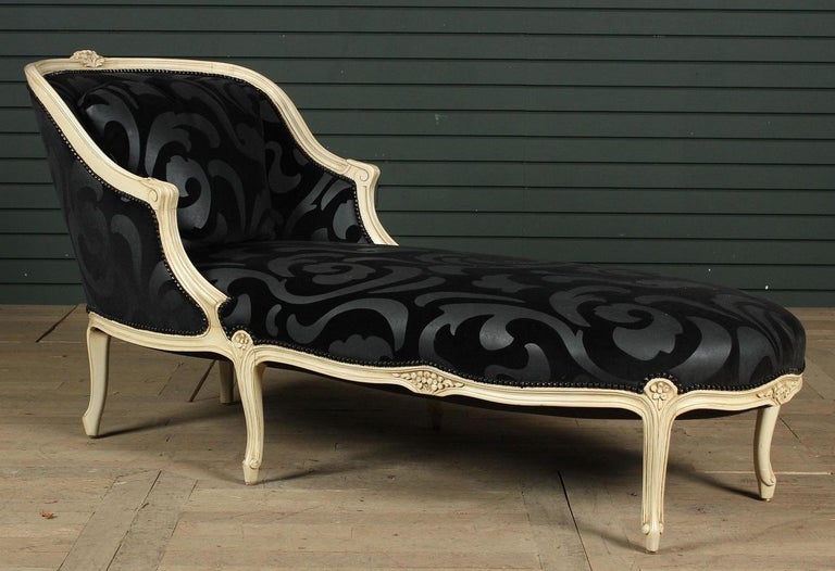 Louis XIV style chaise longue. The chaise has a painted wooden frame with decorative black velour fabric.