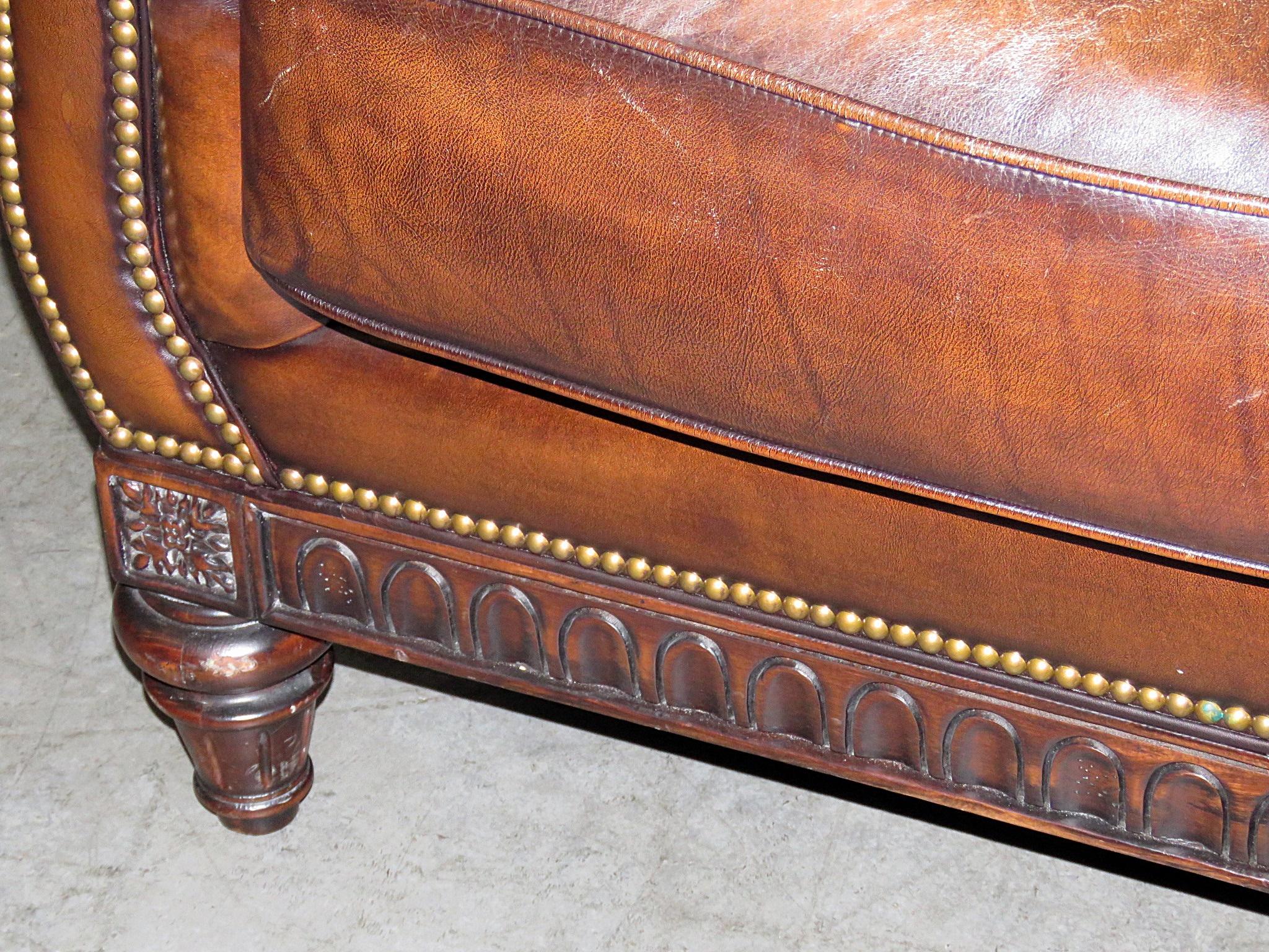 This is a rare form of chesterfield sofa. This one has a Louis XVI carved mahogany frame and not the English style frame with are more used to seeing. The genuine leather is in very good condition and has a classic tobacco hue with an angtiqued