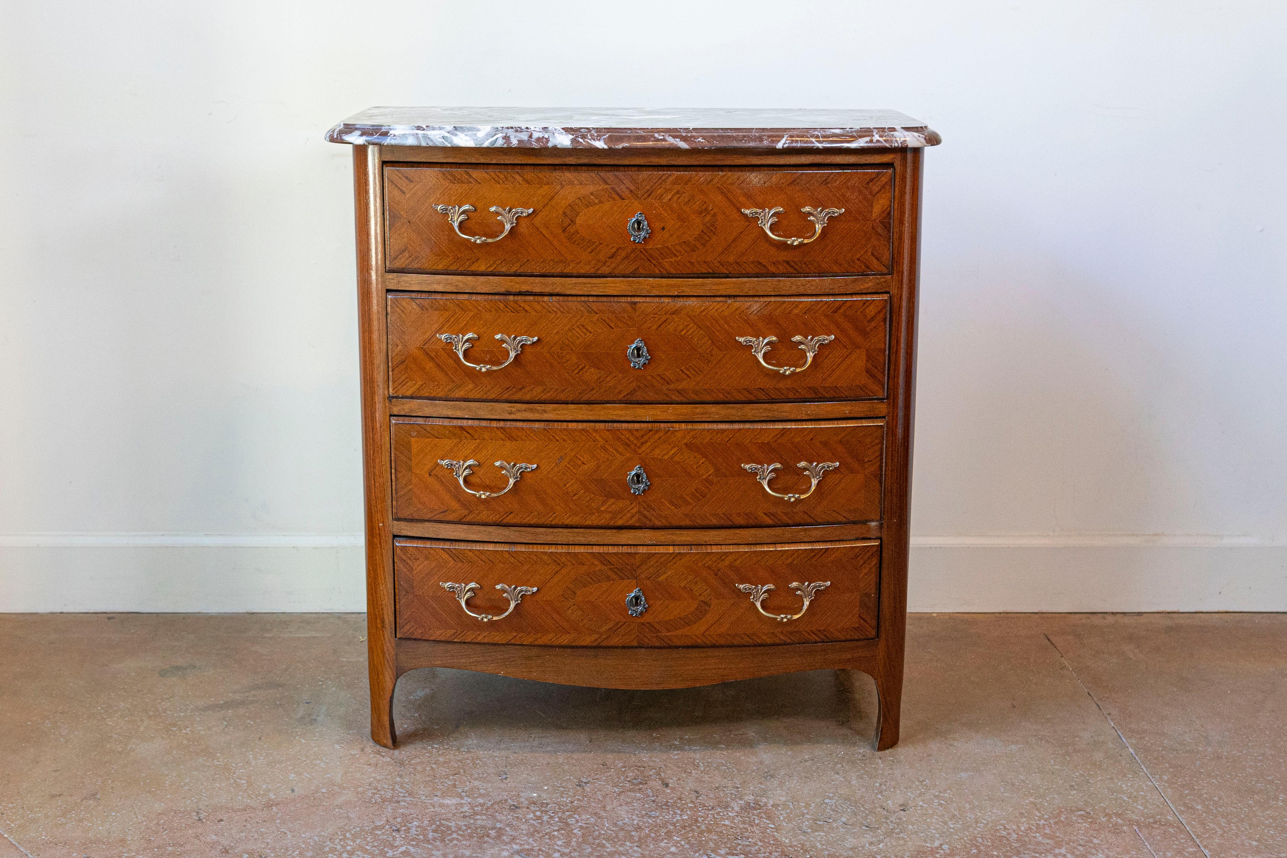 Una commode francese in stile Luigi XIV del 1950 circa con decorazioni in palissandro intarsiato, quattro cassetti, piano in marmo rosso griotte e ferramenta in bronzo dorato. Realizzata nell'intramontabile stile francese Luigi XIV, questa commode